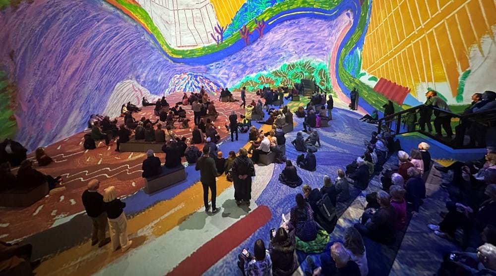 A group of people admire an immersive David Hockney exhibition