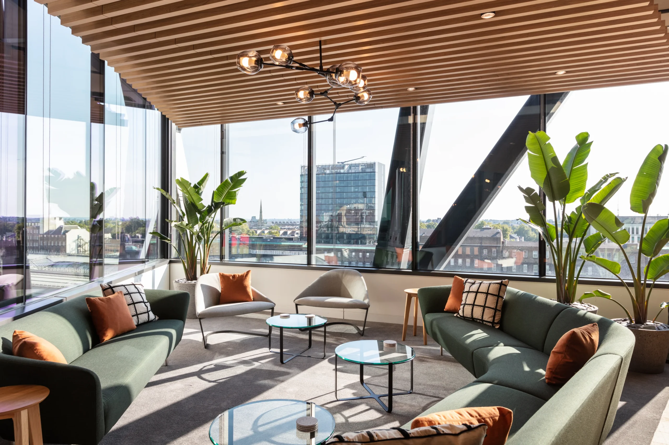 A Guide to Office Relocation featuring Alpha FX's soft sofa seating and plants looking onto the city skyline.