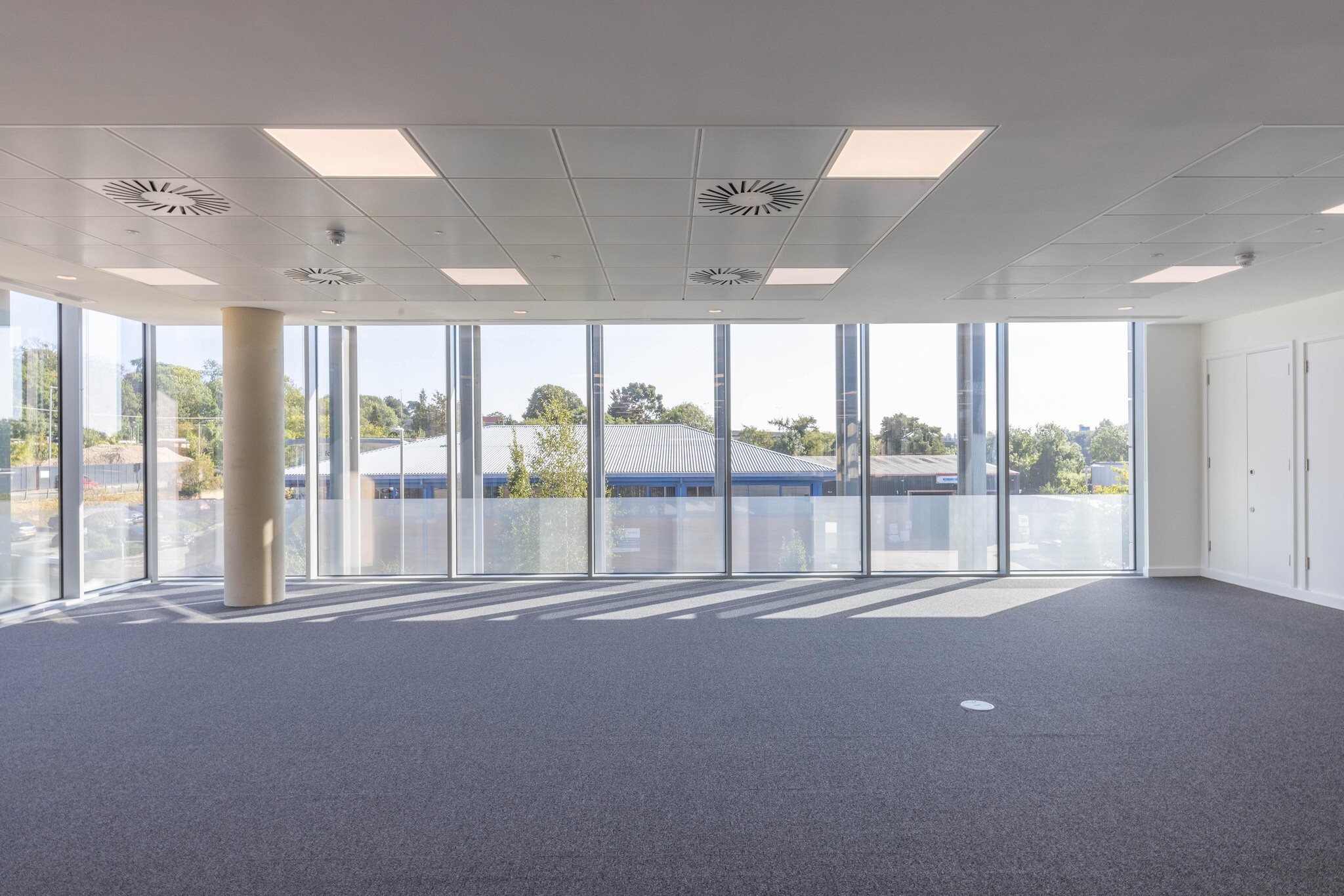 Spacious, open-plan office area at The Dock with large windows letting in natural light and a neutral colour palette.