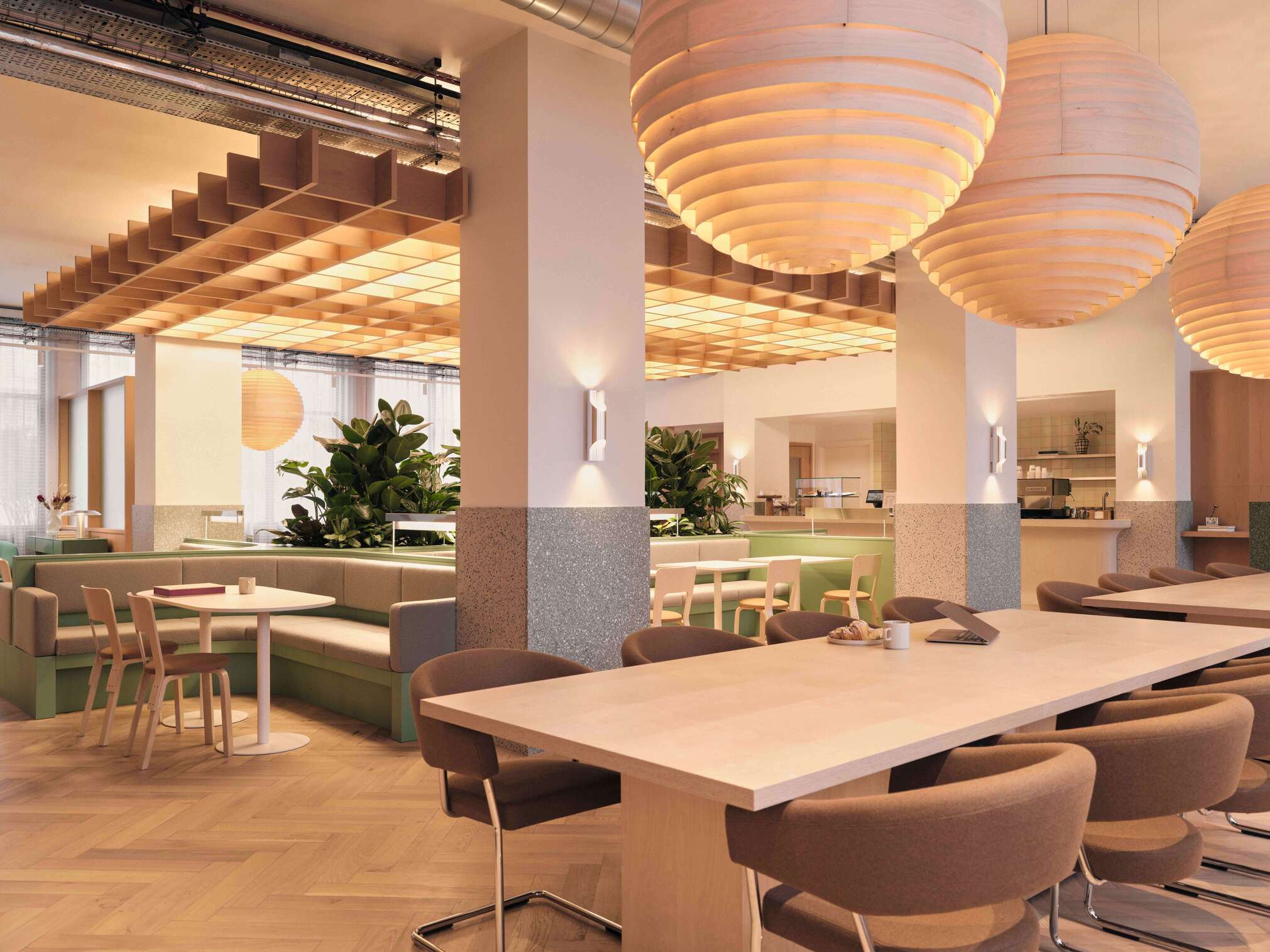 A spacious area designed for dining and collaboration, highlighted by large pendant lights and communal tables. The layout and furniture promote teamwork and informal meetings, with a fresh and contemporary feel.