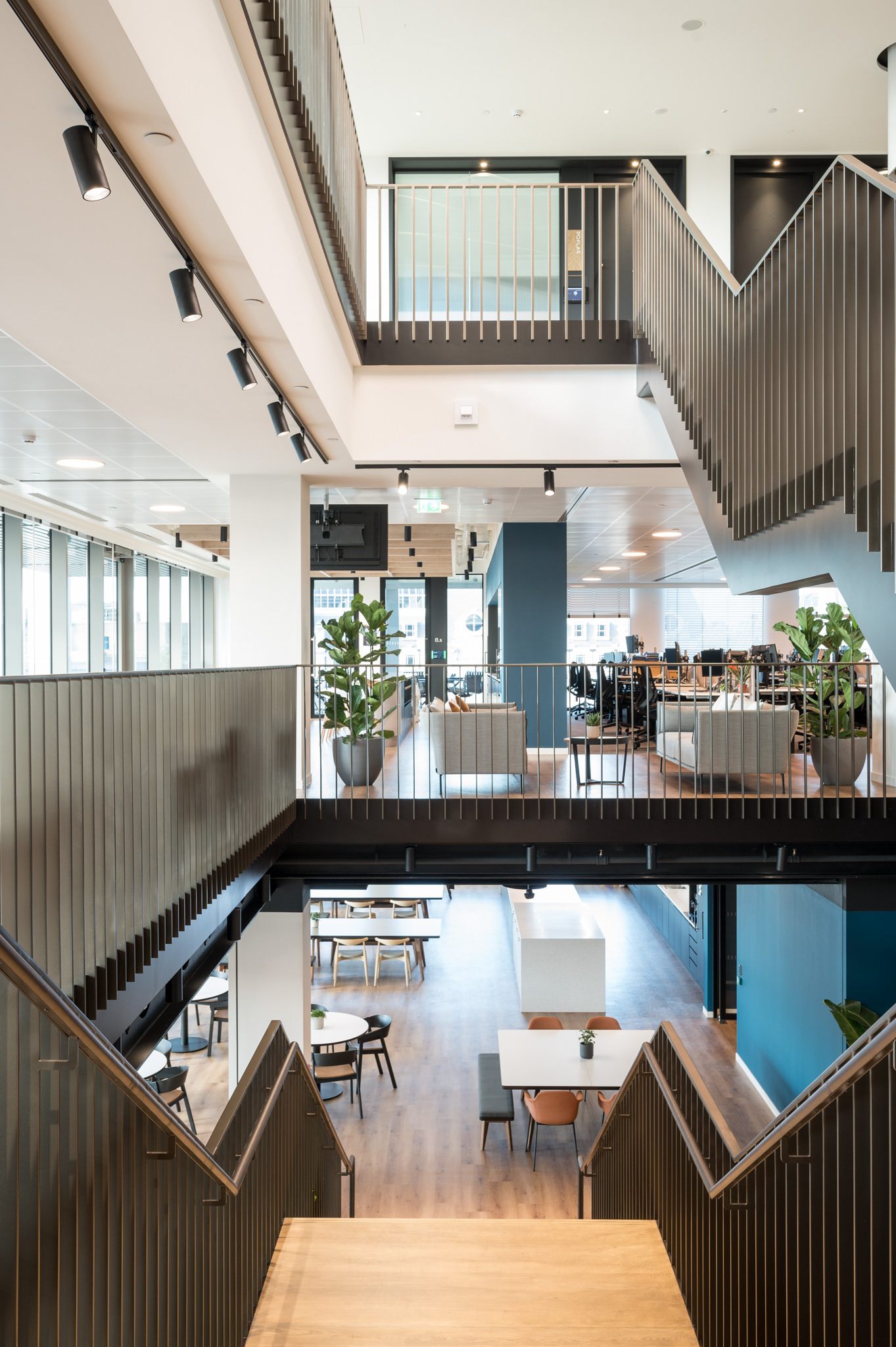 Interior view of Numis' workspace designed by Modus, showcasing a modern, open-plan layout with a central staircase, wooden flooring, and natural light.
