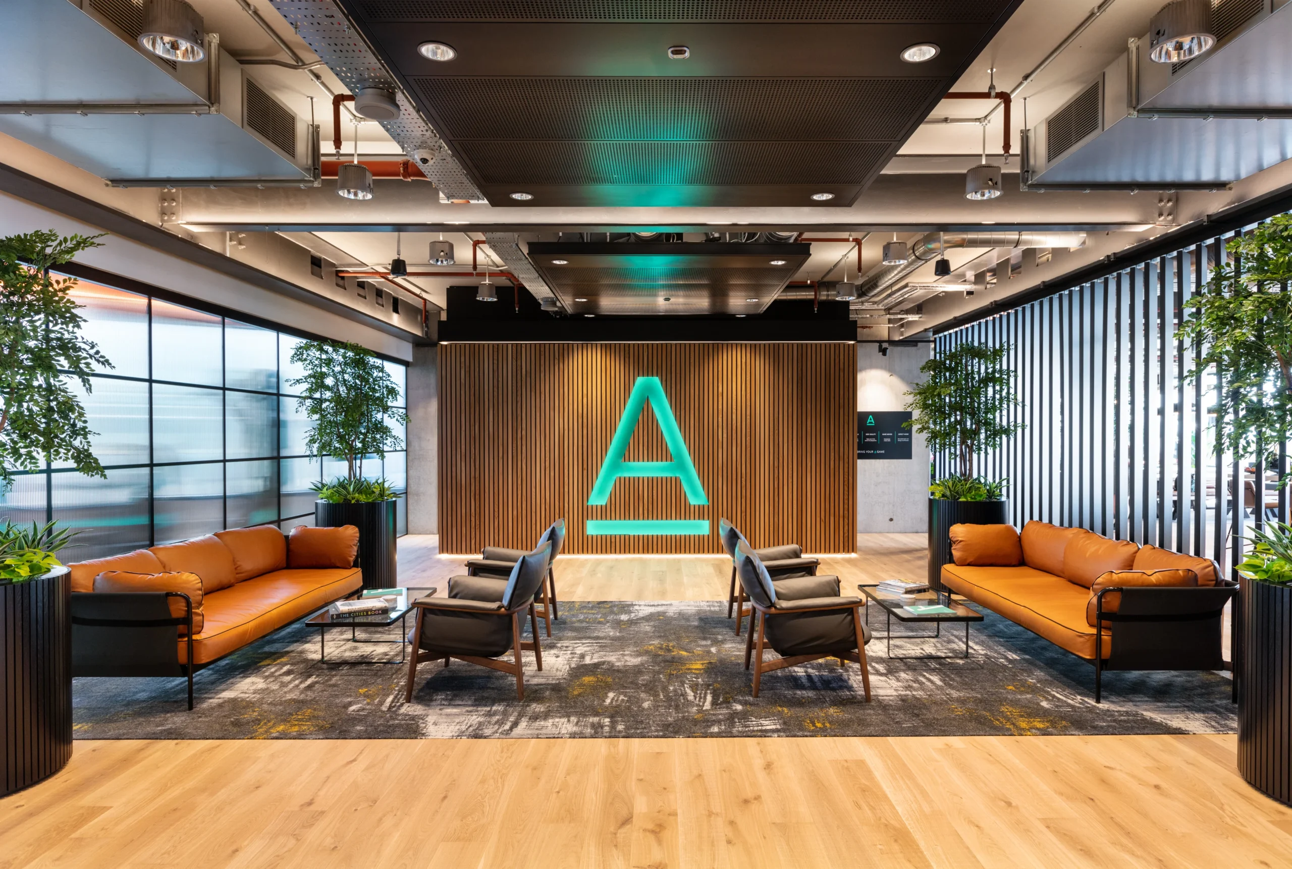 The reception area at Alpha FX, featuring modern furnishings, biophilic design, and a striking illuminated logo, optimised for both style and functionality