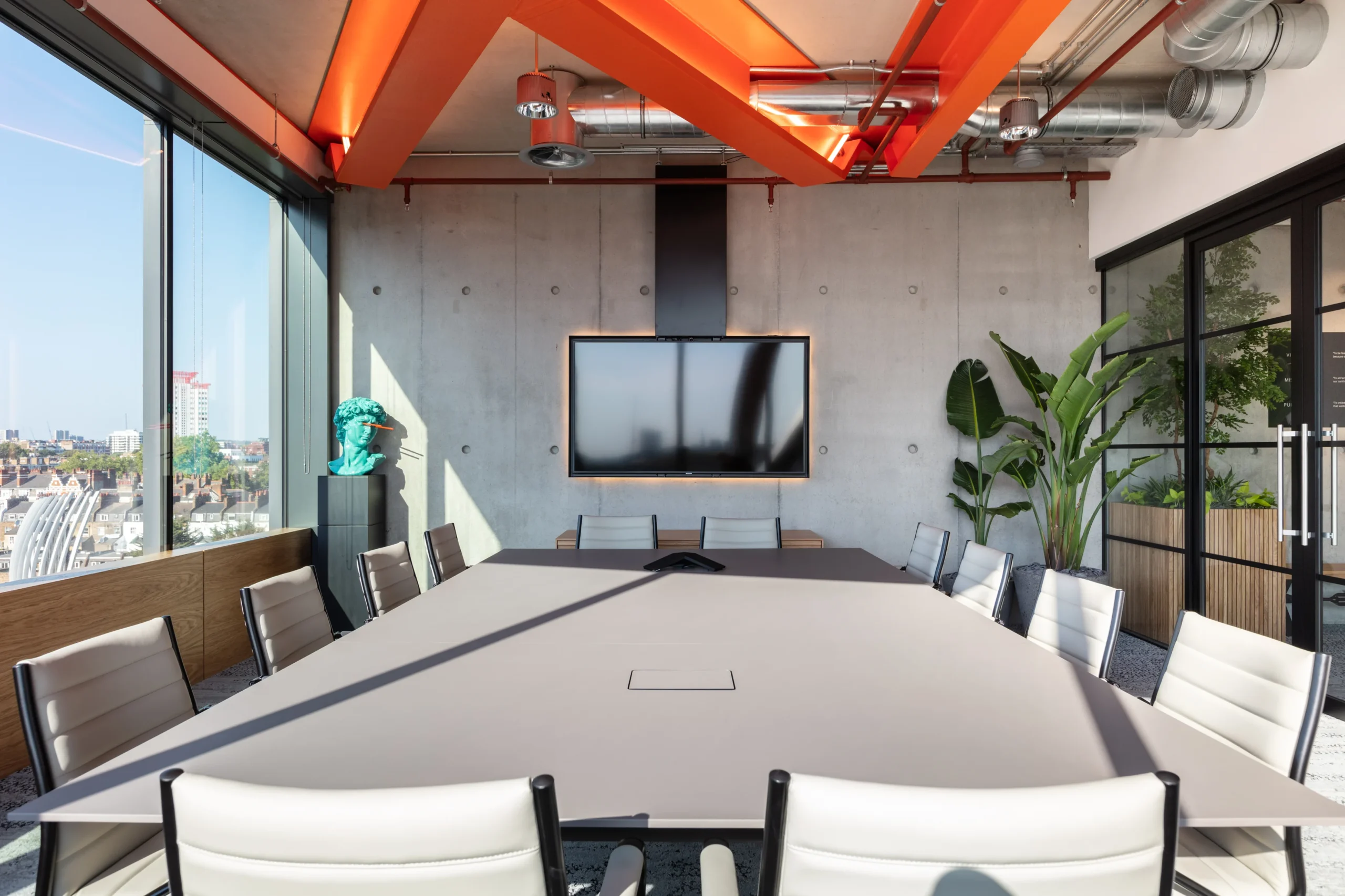 Alpha FX open meeting room with white office chairs, open glass windows and large plants decorating the corner of the room.