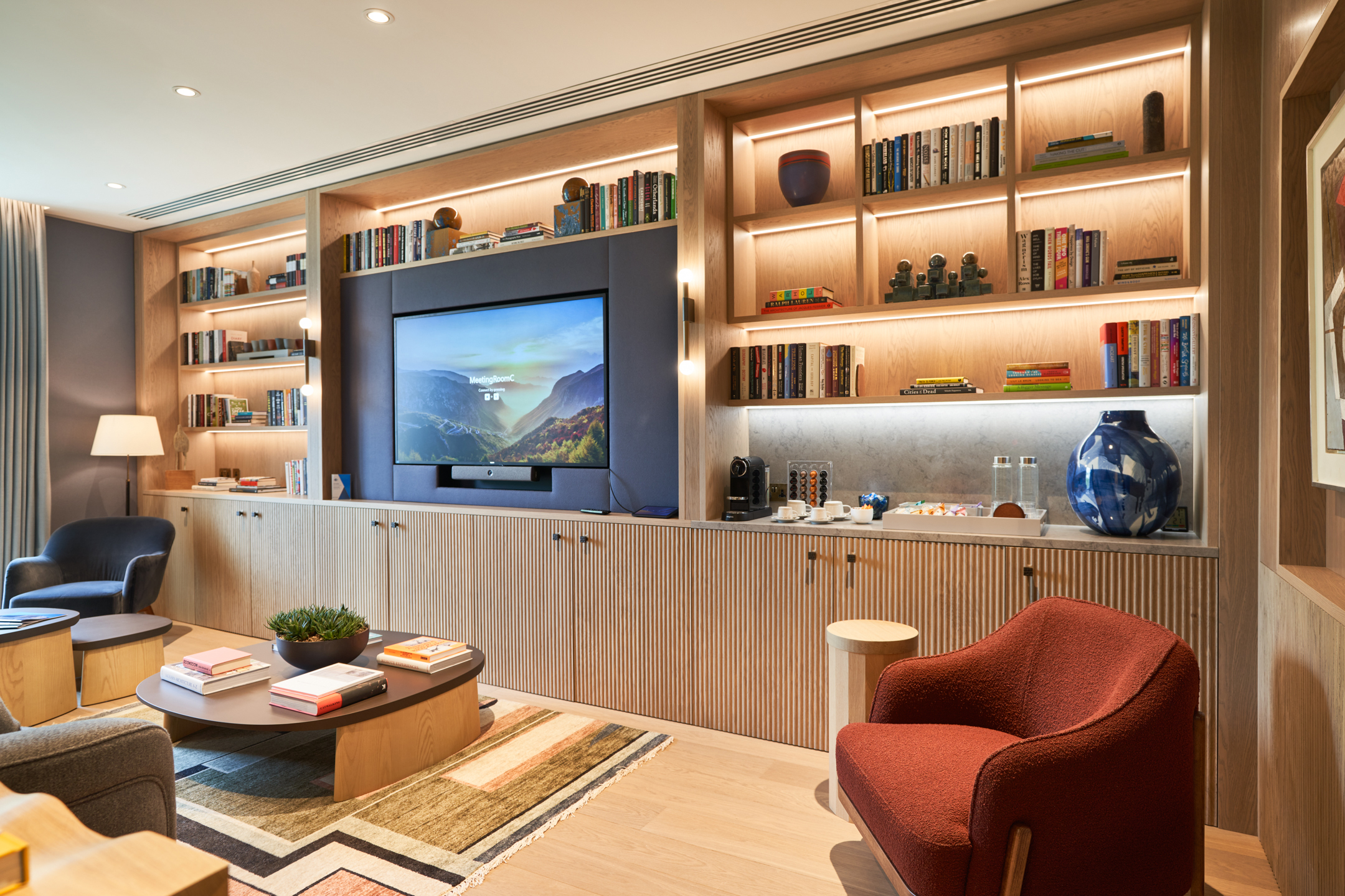 A warm, inviting reading room at Asset Management Firm, featuring built-in bookshelves and soft lighting designed by Modus Workspace.