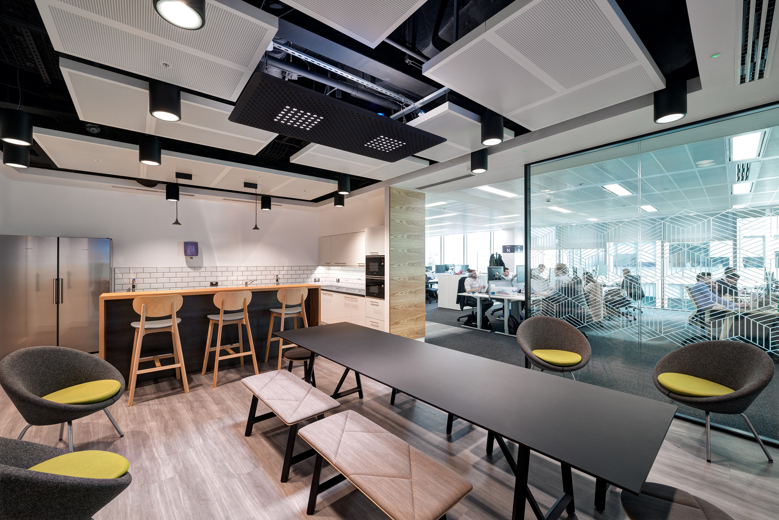 A teapoint in Atkins' Nova North workplace with manifestations on the glazing and soft seating with pops of green.