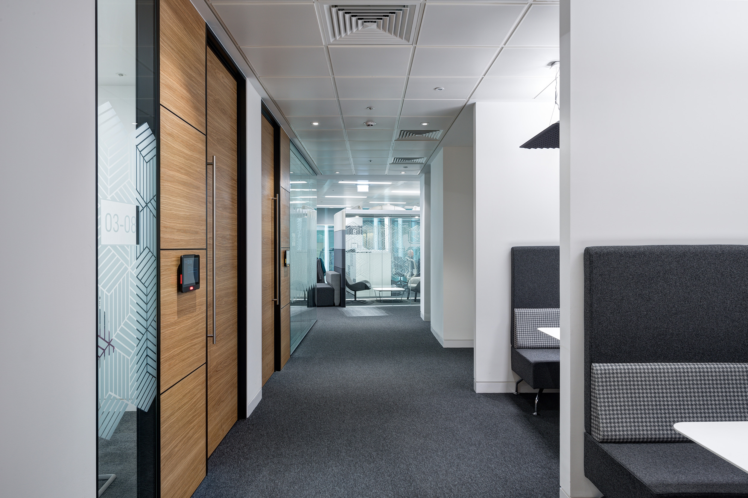 A sleek office corridor at Atkins' Nova North featuring wooden doors and stylish glazing partitions in the meeting rooms.