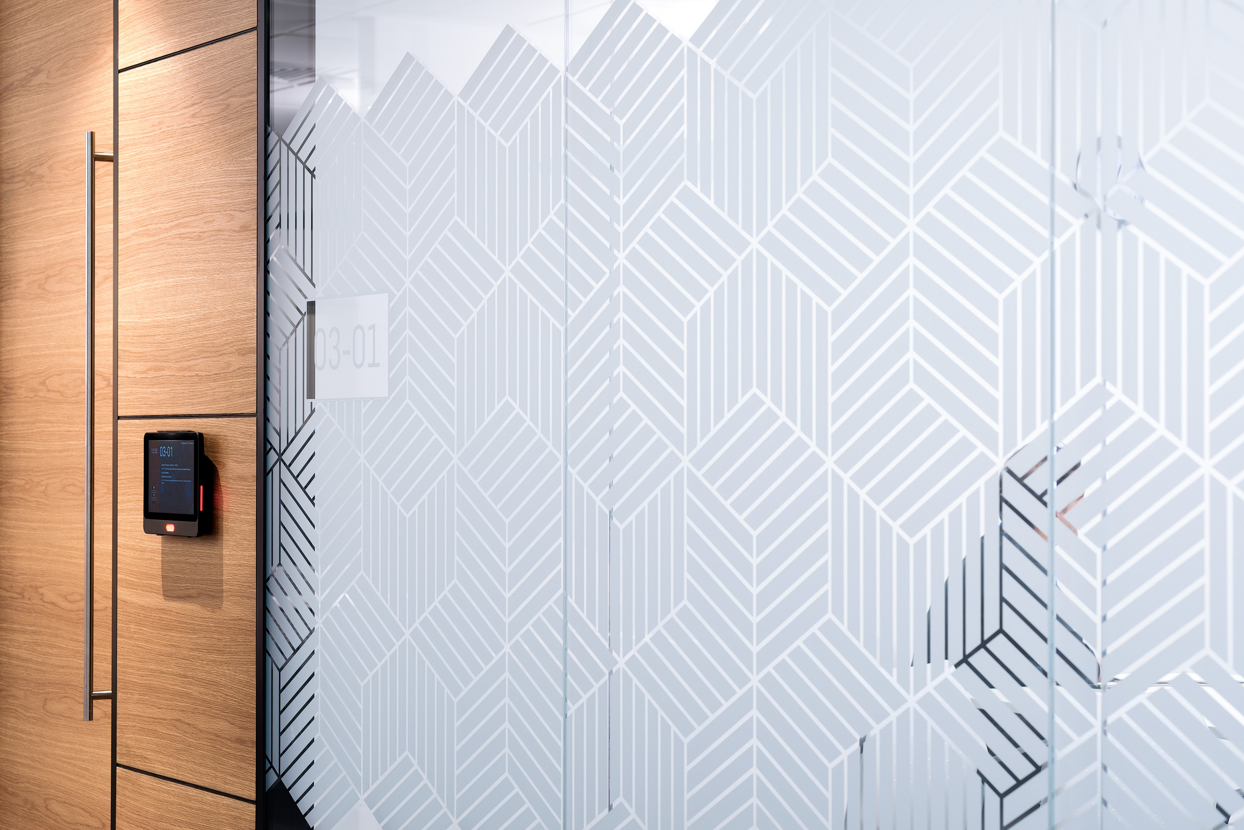A close-up of a meeting room door and the frosted geometric manifestation pattern at Atkins' Nova North office.