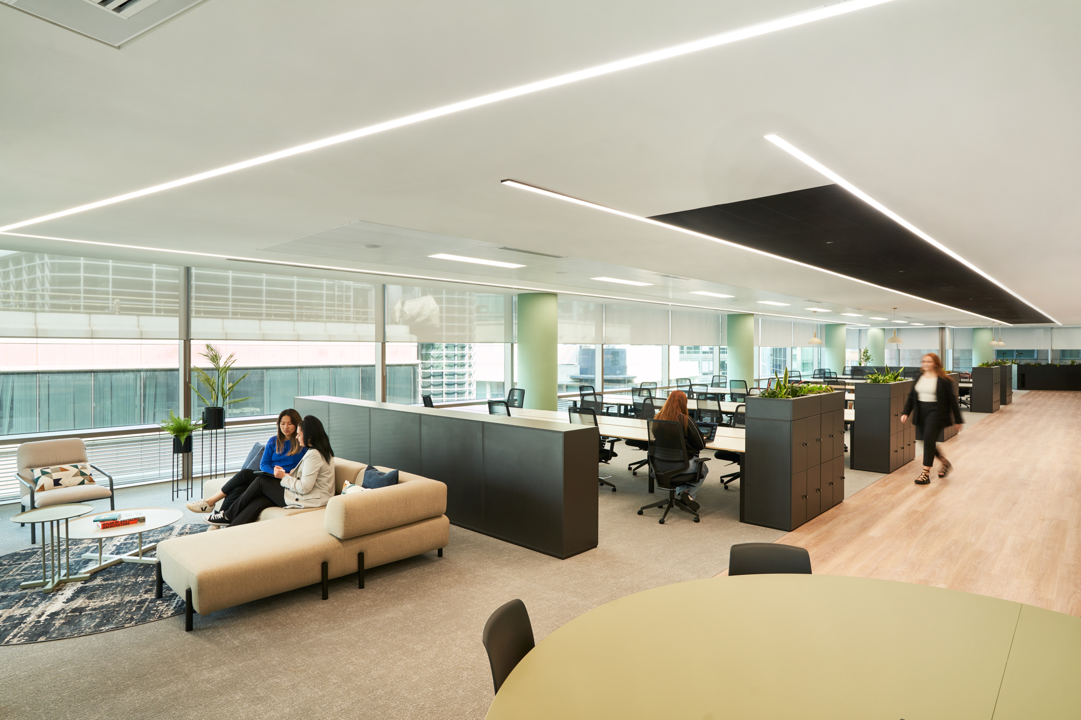 An expansive open-plan office at British Land's 10 Exchange Square, designed by Modus Workspace, featuring workstations and casual seating areas. People are working and interacting in the collaborative environment.