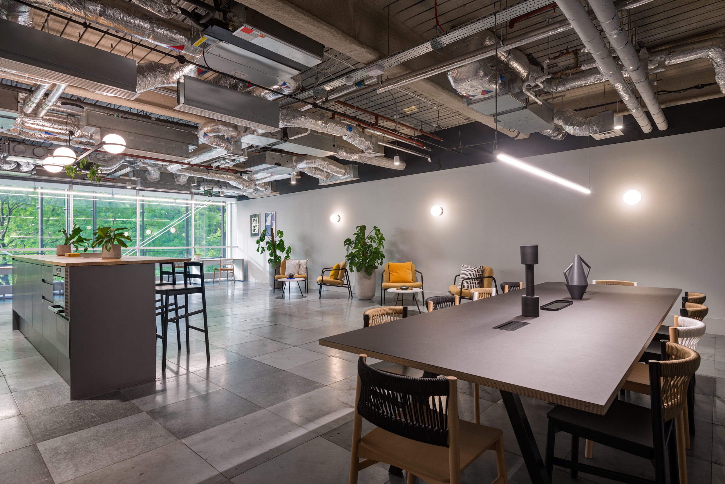 A spacious, light-filled communal area in the British Land office at 3 Finsbury Avenue, designed by Modus Workspace. The space is furnished with comfortable seating and a large table, ideal for both work and relaxation, underlined by a modern, industrial aesthetic.