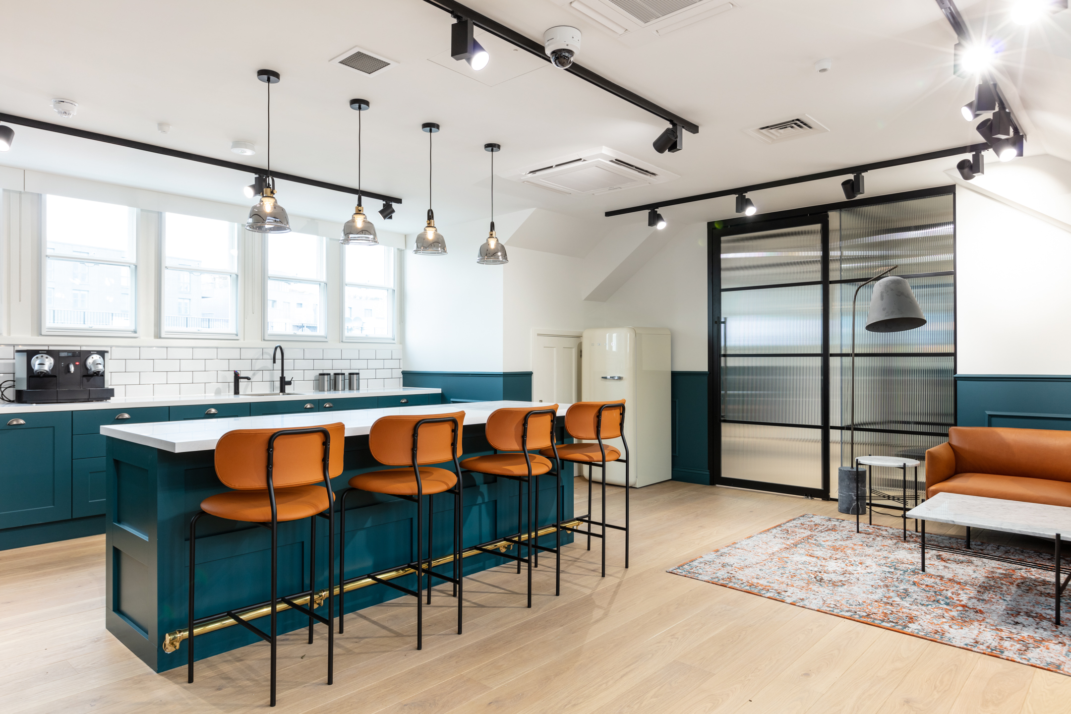 Cain International green, orange and gold open teapoint with white walls and hanging lights.