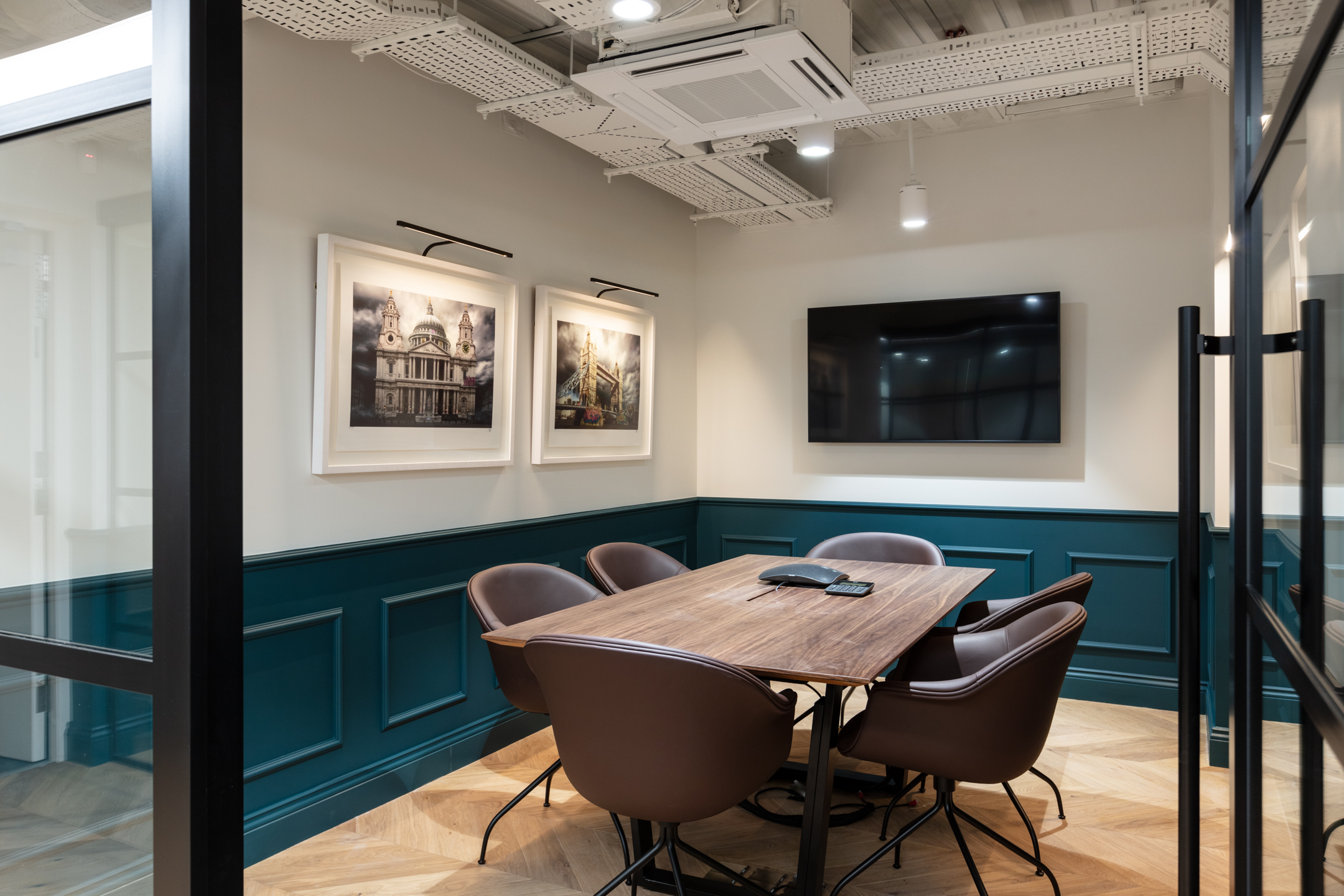 Cain International small meeting room with a regal aesthetic, hanging art and a large screen.