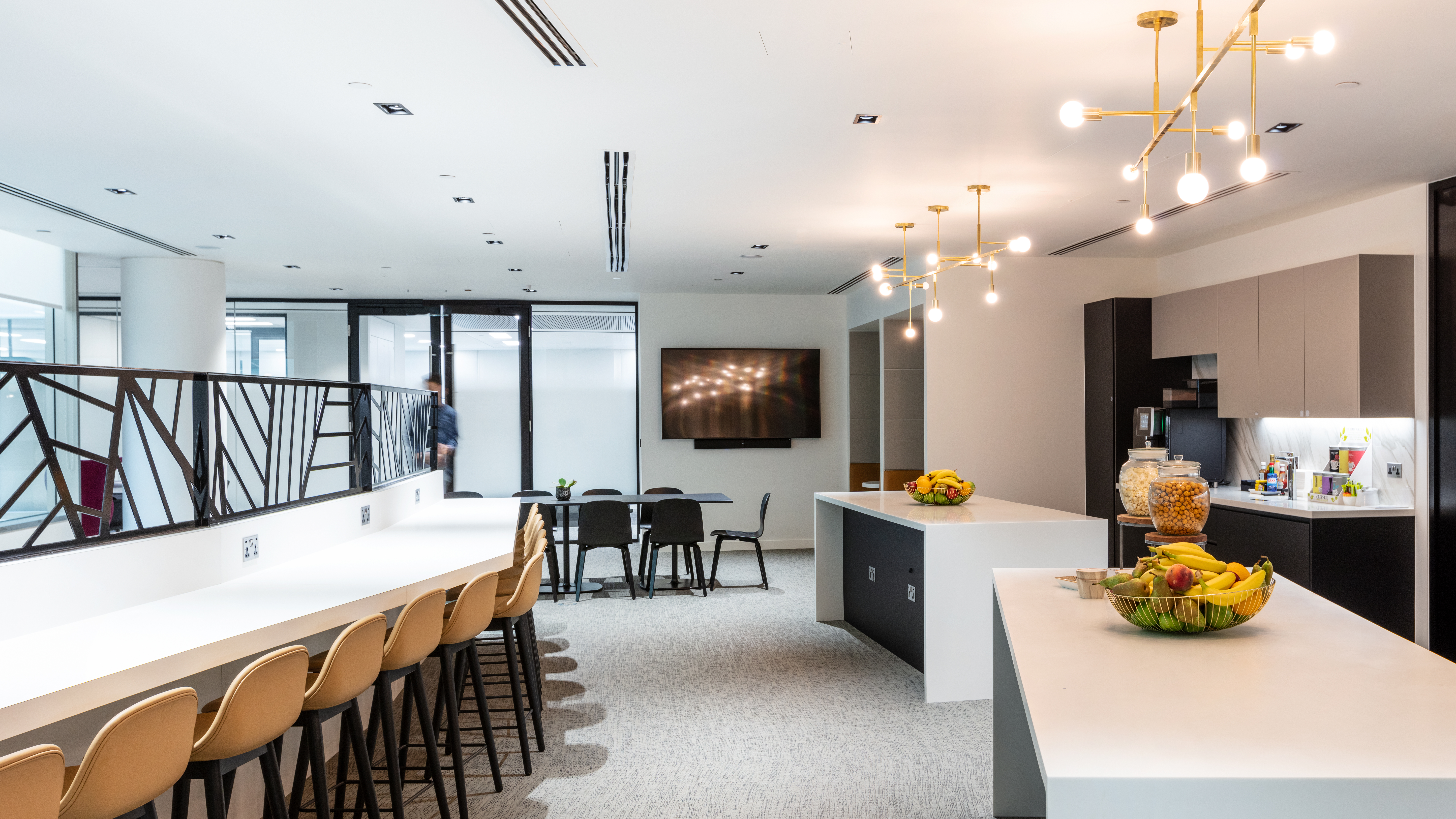 The teapoint area at Houlihan Lokey combines functionality and style, with ample seating and modern lighting fixtures. Modus Workspace's design encourages collaboration in a comfortable, inviting setting.
