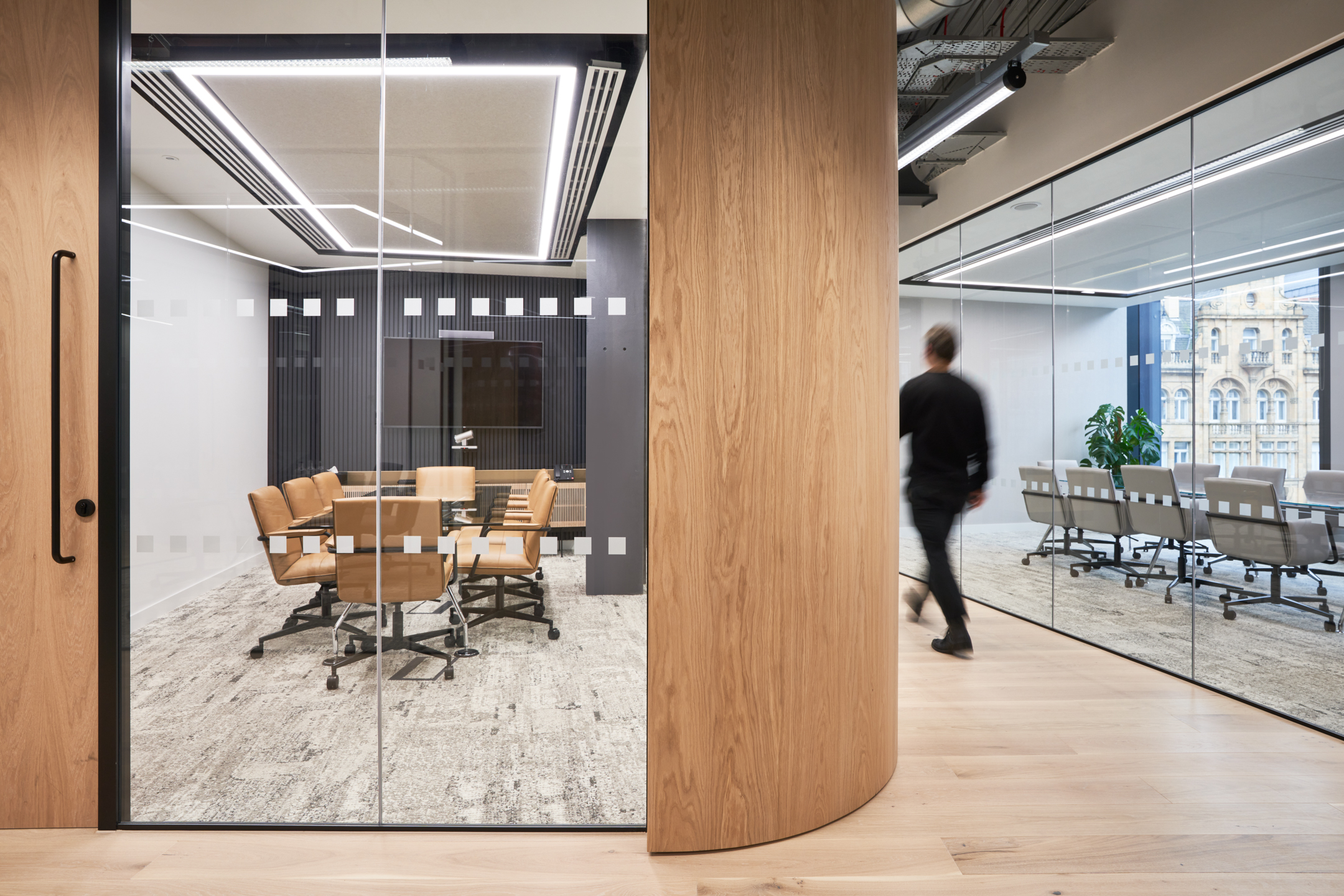 Investment Firm open glass meeting rooms, featuring a curved hallway, creating a sleek and professional feel.