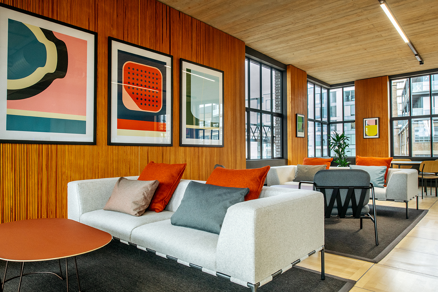 Joseph Joseph seating area with large hanging art, oak walls and cushions.