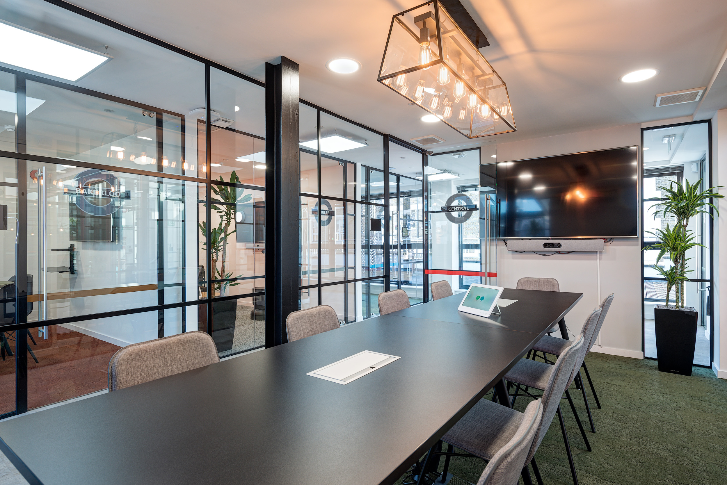 Kayak’s office conference room, designed by Modus Workspace, features a sleek black table, modern lighting, and glass walls, offering a private and professional setting for meetings.