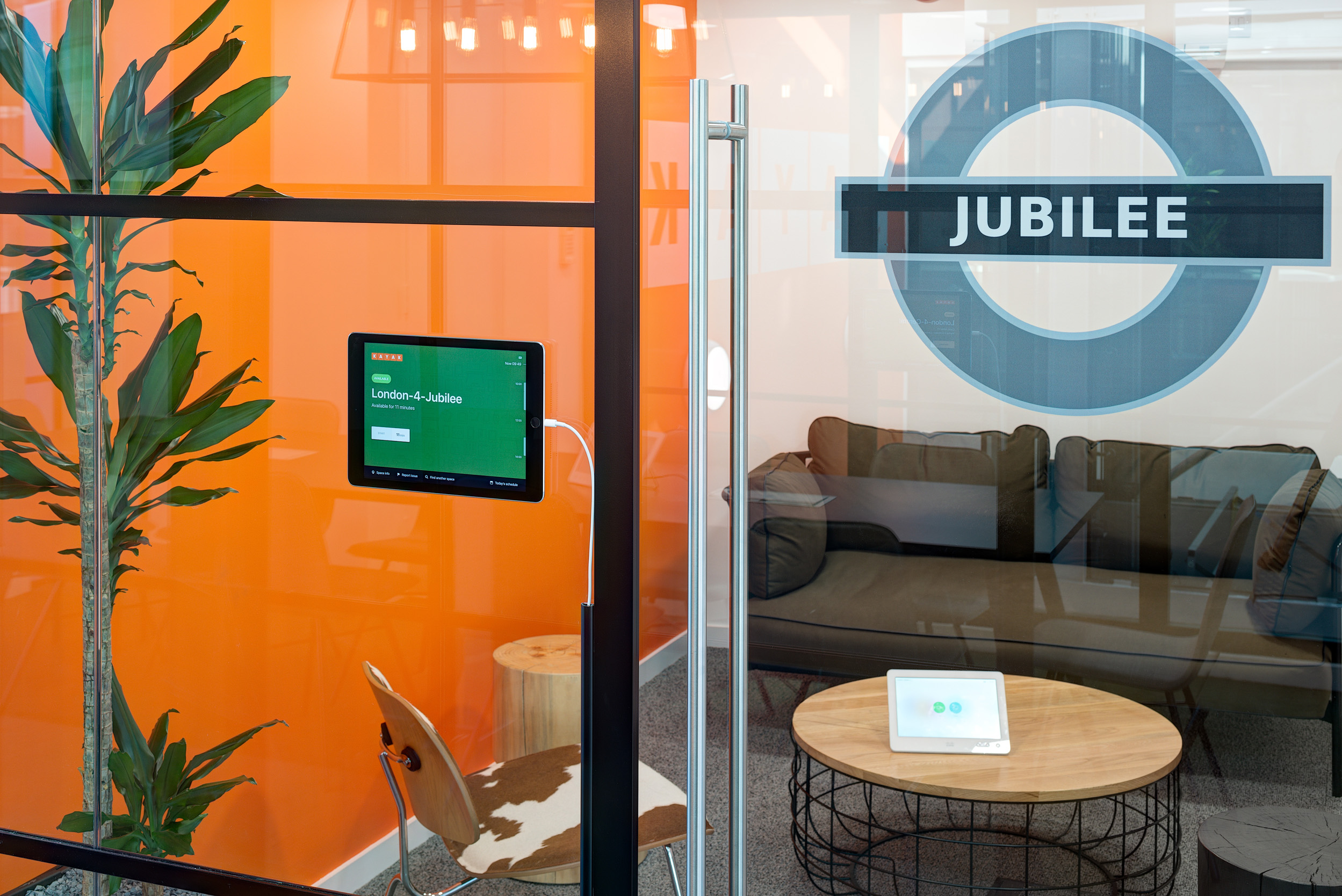 Kayak's Jubilee-themed meeting room, designed by Modus Workspace, has vibrant orange decor and a cozy seating arrangement, creating an inviting and colourful space for collaboration.