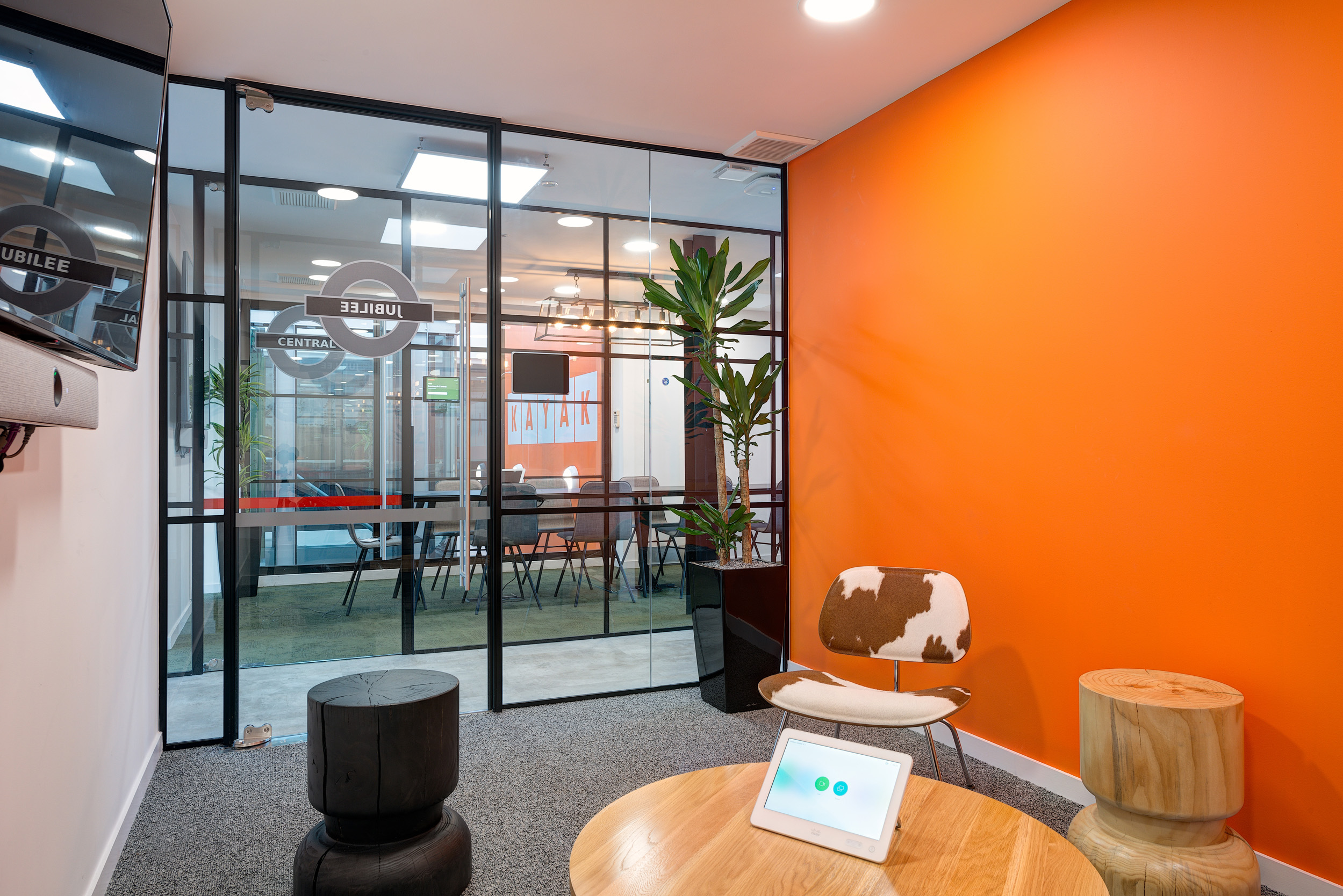 The themed meeting rooms, designed by Modus Workspace, at Kayak's office include London subway-inspired designs with bold colours and glass partitions, creating unique and inspiring workspaces.