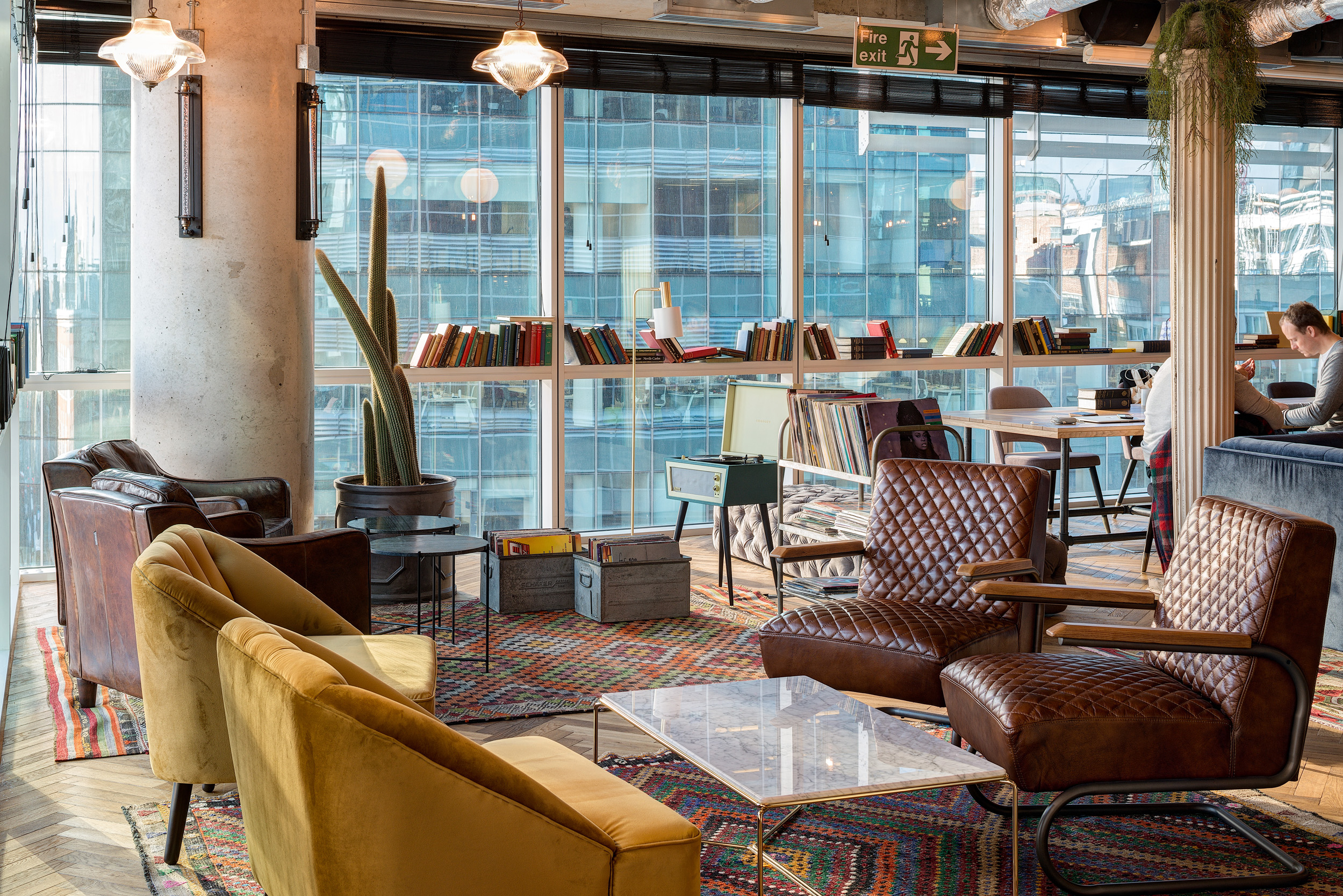 An inviting lounge space with leather armchairs, cactus plants, and floor-to-ceiling windows at Mindspace 144 Whitechapel, designed by Modus Workspace.