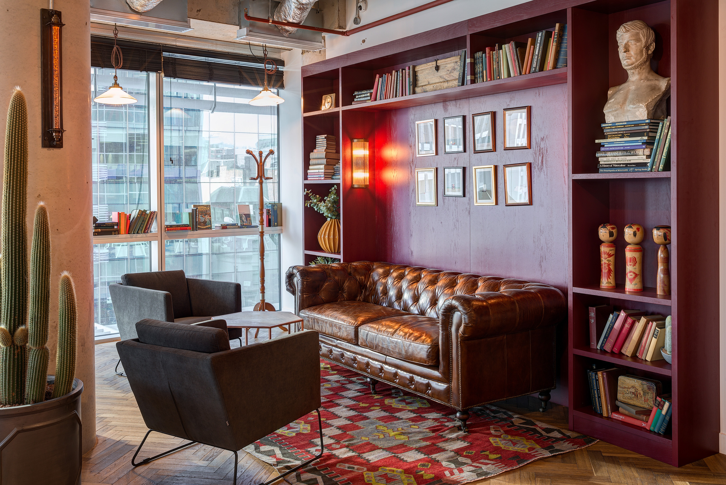A breakout area with a leather Chesterfield sofa and wooden bookshelves, creating a warm, vintage vibe at Mindspace 144 Whitechapel, designed by Modus Workspace.