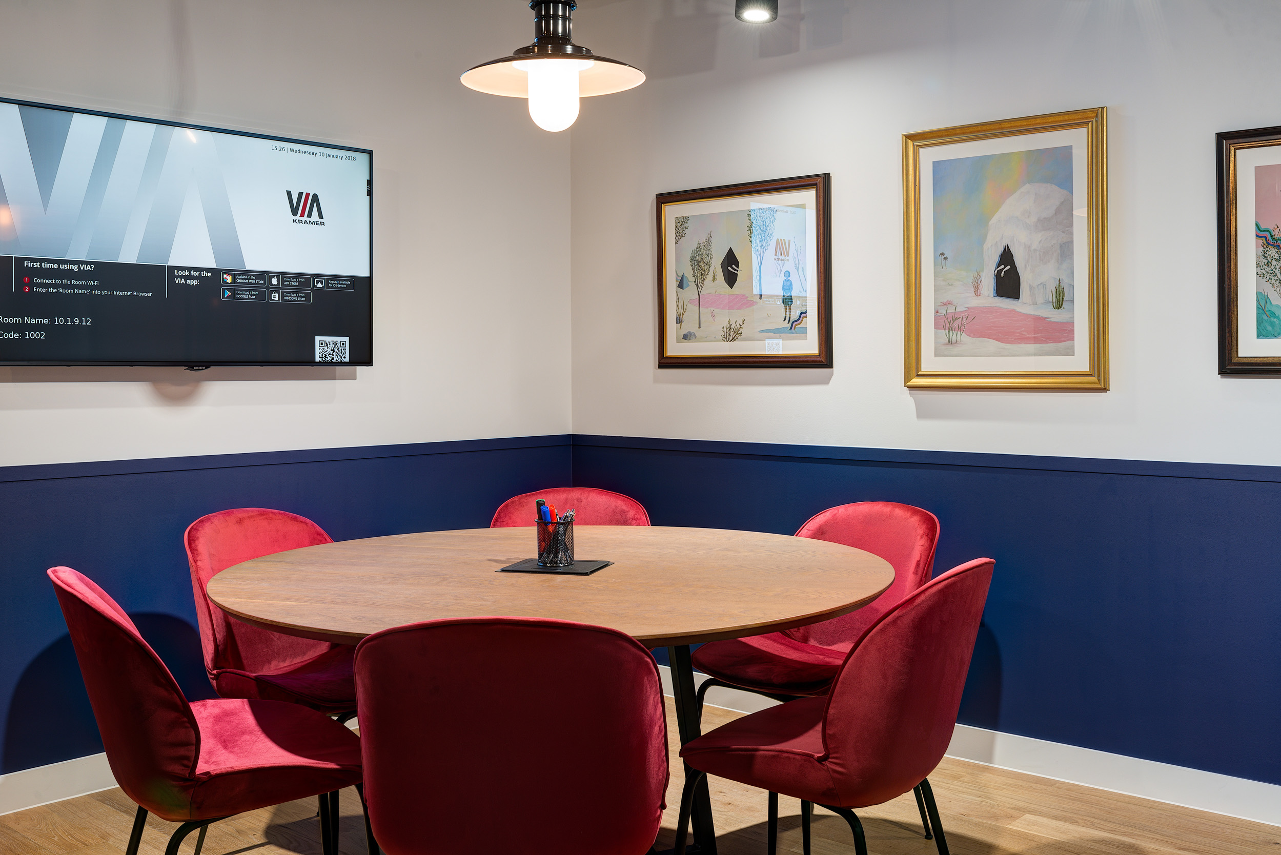 A small, private meeting room with a round table and red velvet chairs at Mindspace 144 Whitechapel, designed by Modus Workspace.