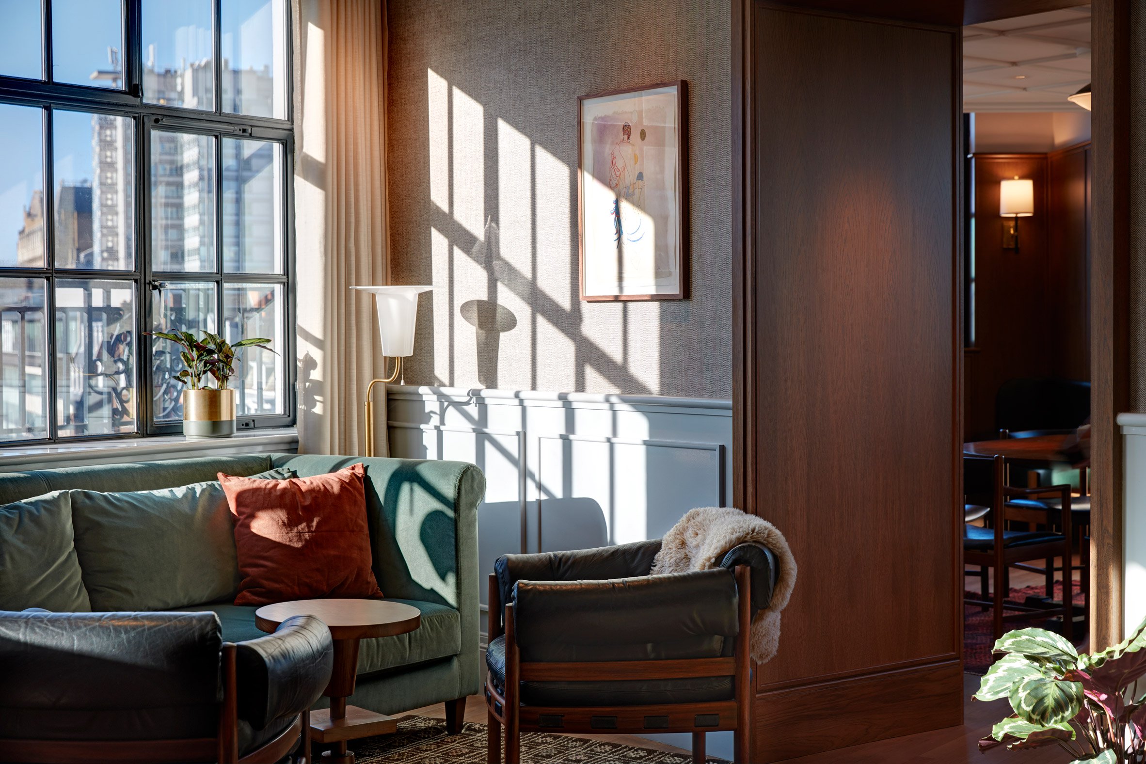 Mortimer House soft seating area next to hanging art, and an open view of the city.