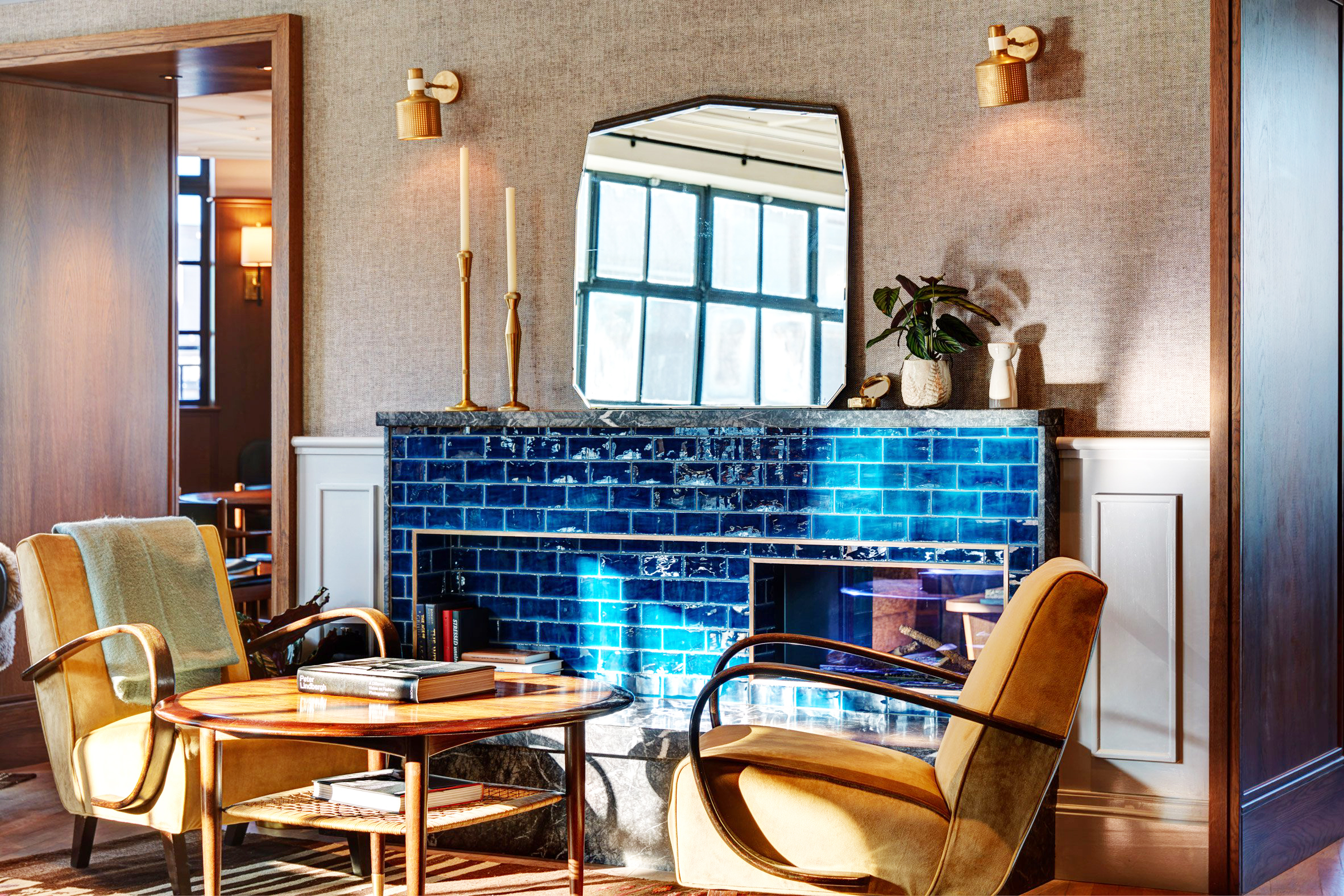 Mortimer House seating area with blue tiled fireplace, gold seats and eclectic mirrors.