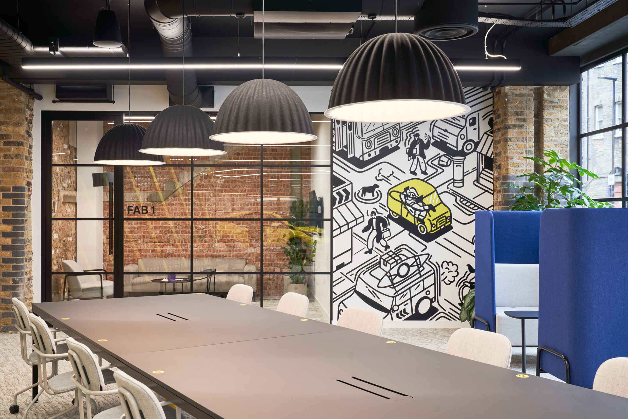 Motorway meeting room and workspace, with a large graphic wall, hanging lights and quiet pods.