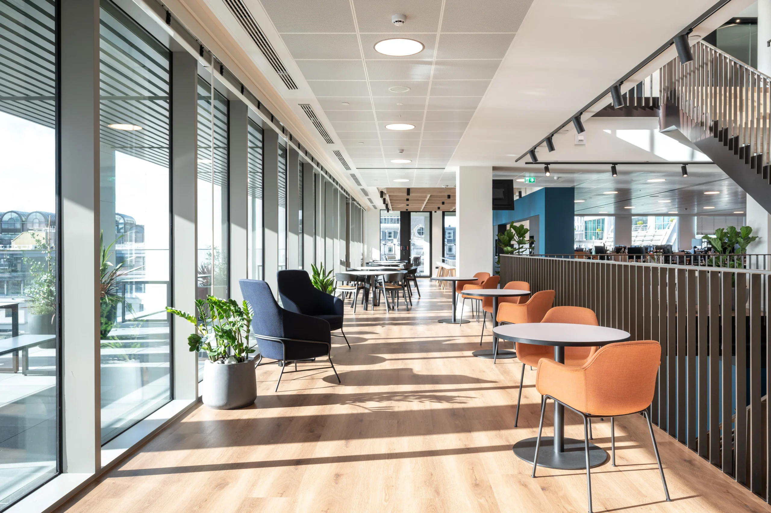 Numis workspace featuring an open - plan seating area, branded coloured seating and metal rails.
