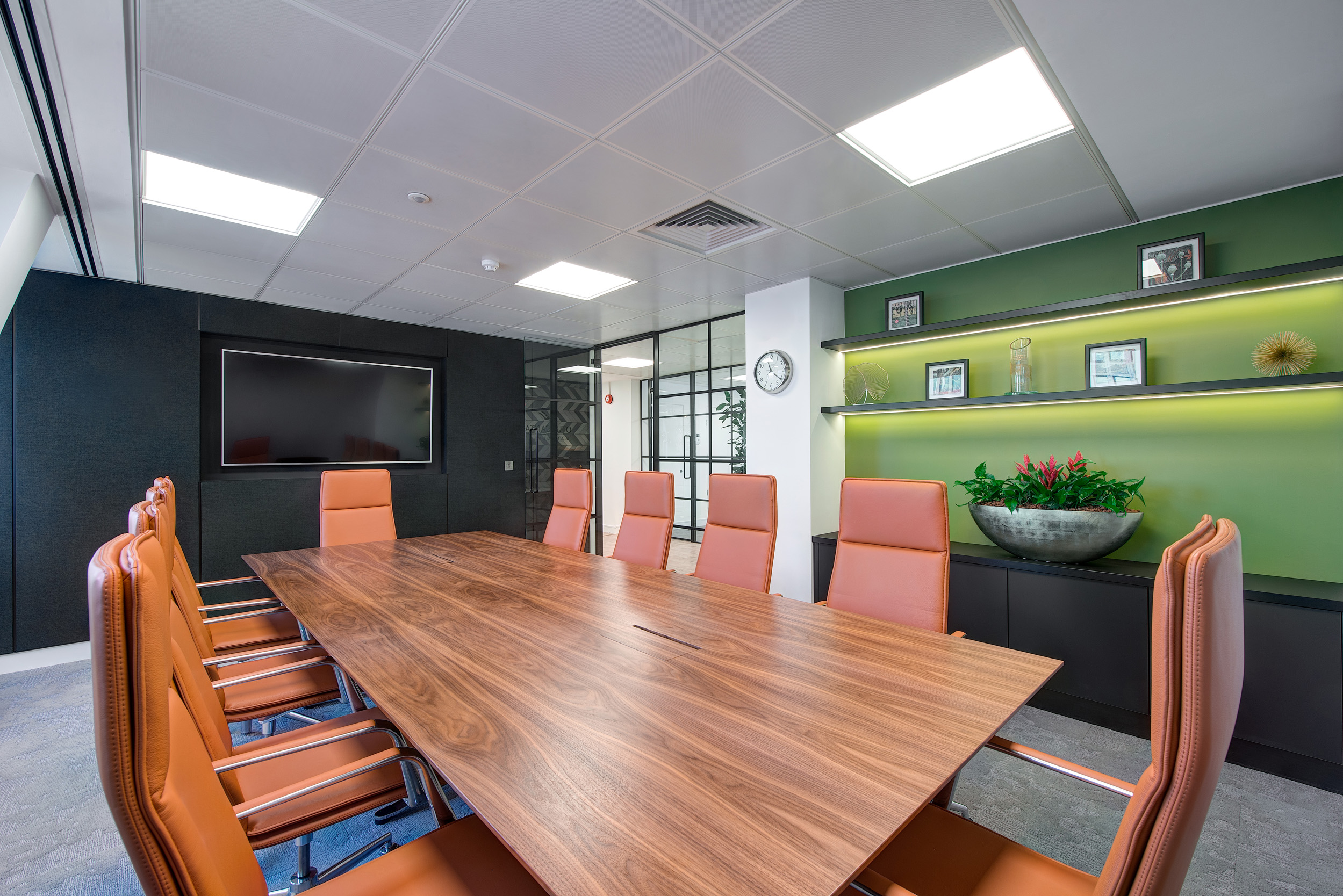 A meeting room at Otus Capital Management, designed by Modus Workspace, featuring a large walnut table surrounded by ergonomic leather chairs, with built-in shelving and modern lighting enhancing the professional atmosphere.
