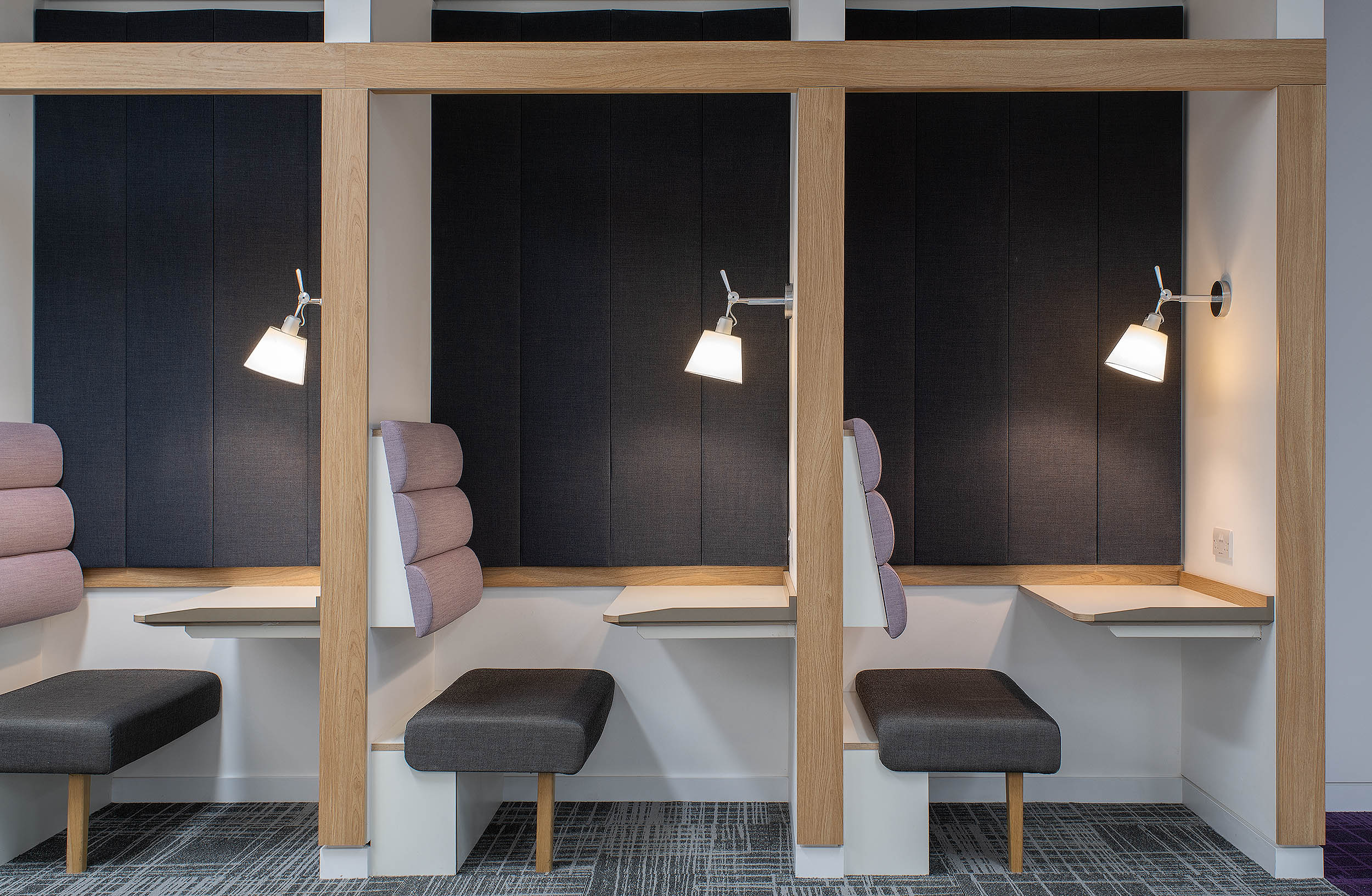 Small, enclosed focus pods at RICS with dark grey seats, wooden frames, and individual lights.