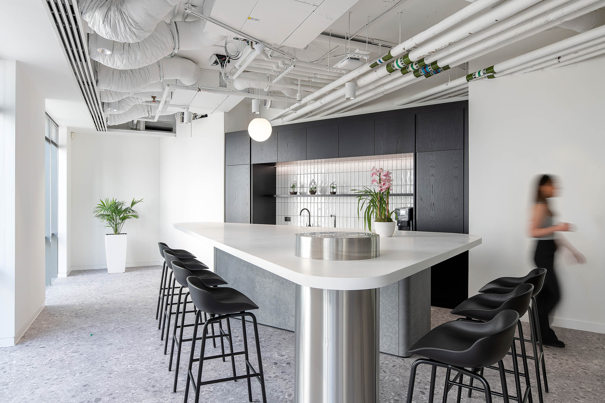 Rakuten white, grey and black teapoint, with high black seats, pink orchids, and white splashback tiles.