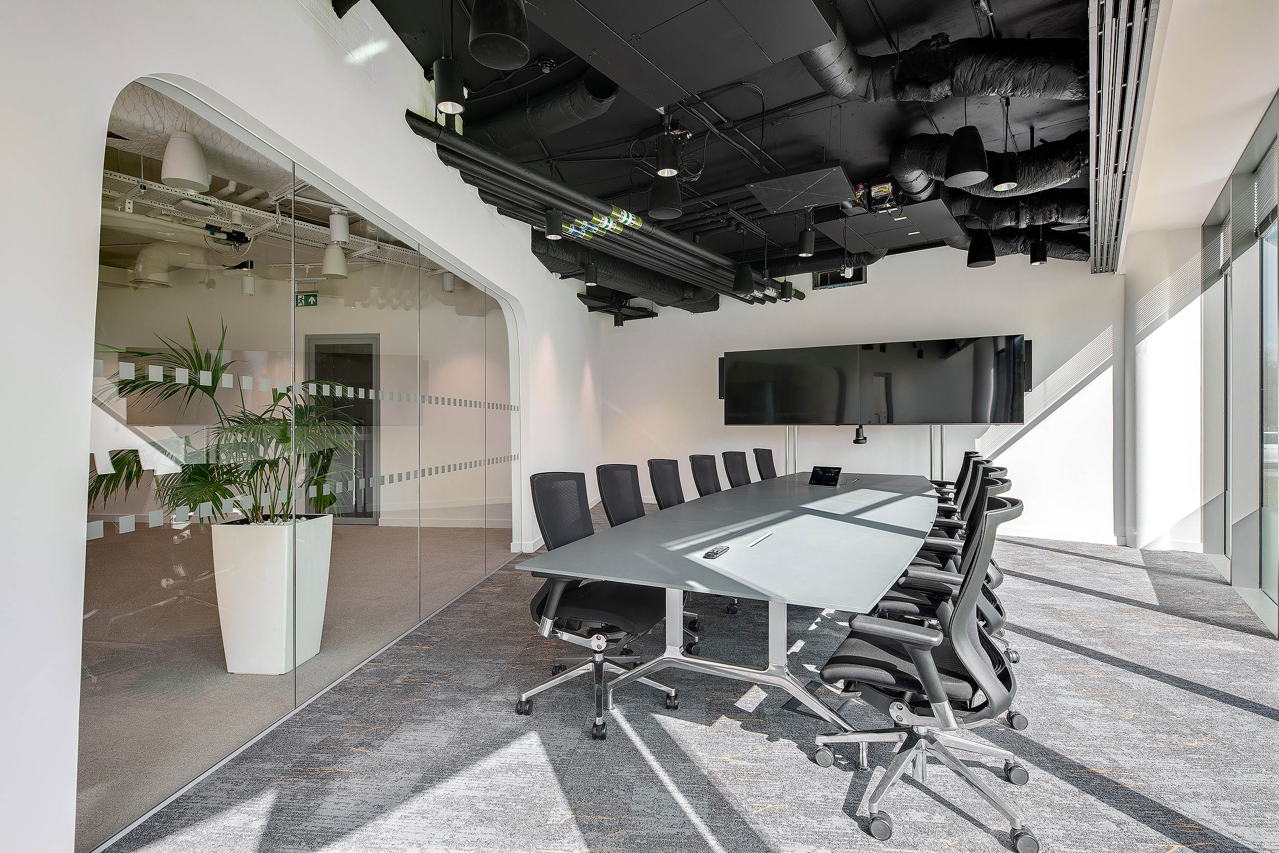 Open boardroom at Rakuten with large double screens, half an oval meeting room table and large black office seats.