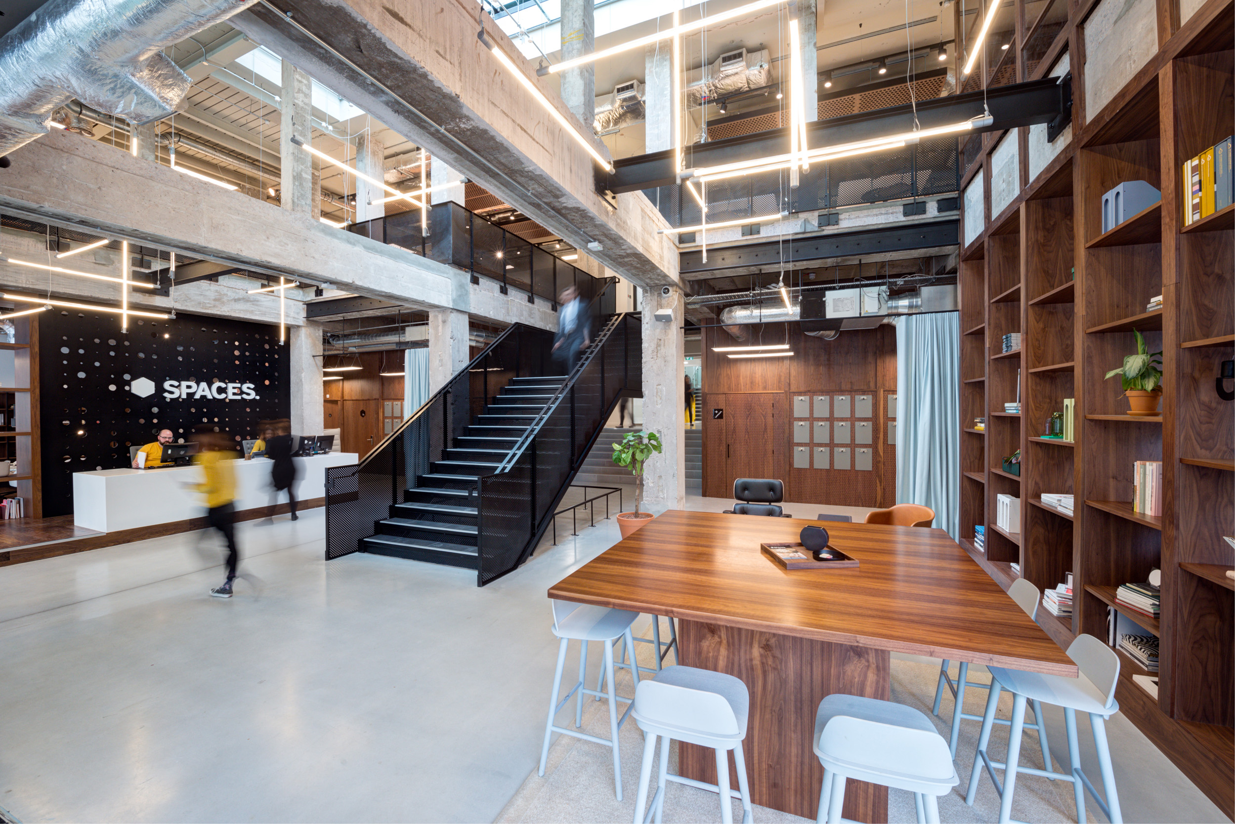 The industrial-style lobby at Spaces Peter House has exposed concrete beams, metal stairs, and a minimalist reception area.