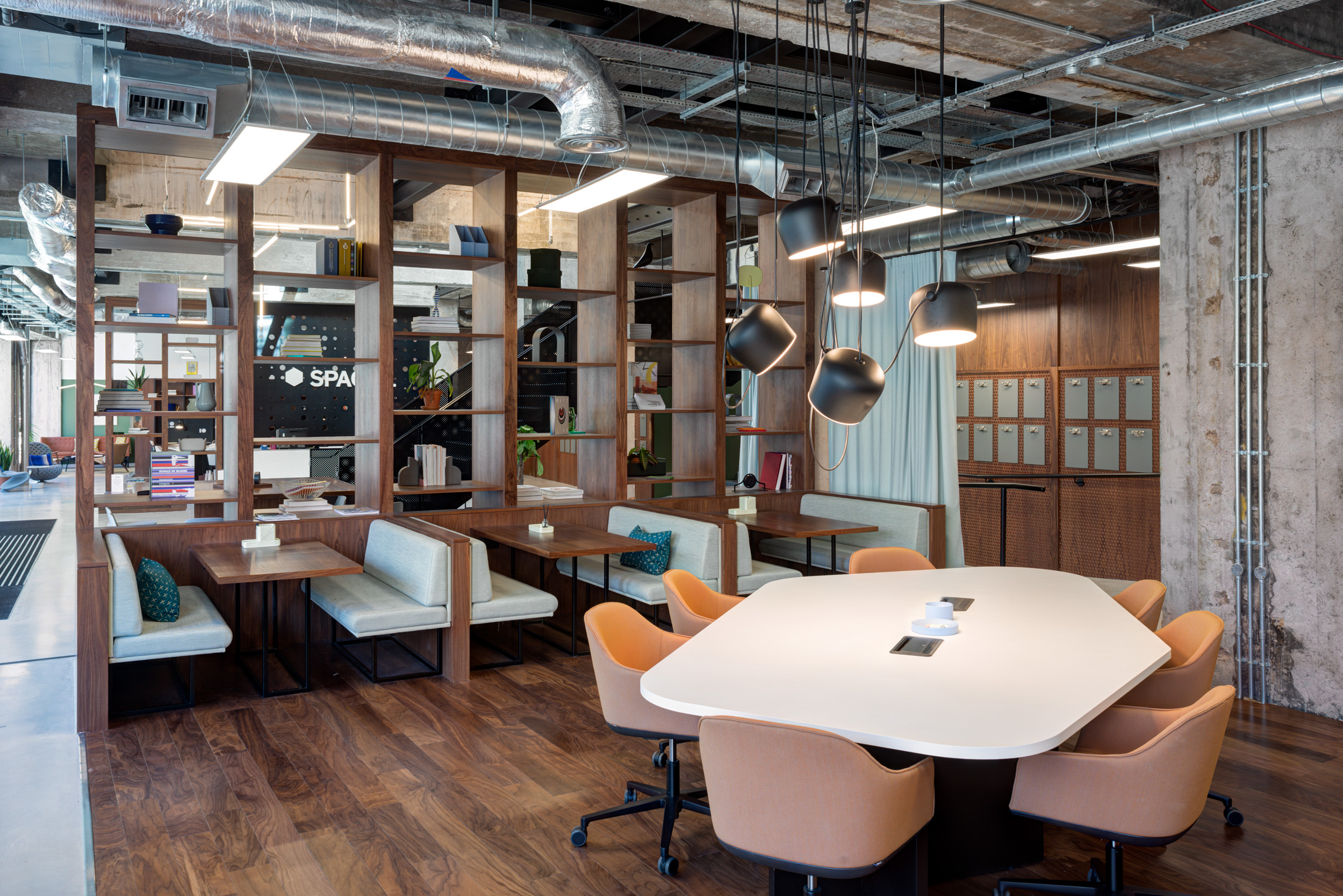 Seating booths and a pentagon worktable with pendant lighting at Spaces Peter House, featuring wood accents and industrial finishes.