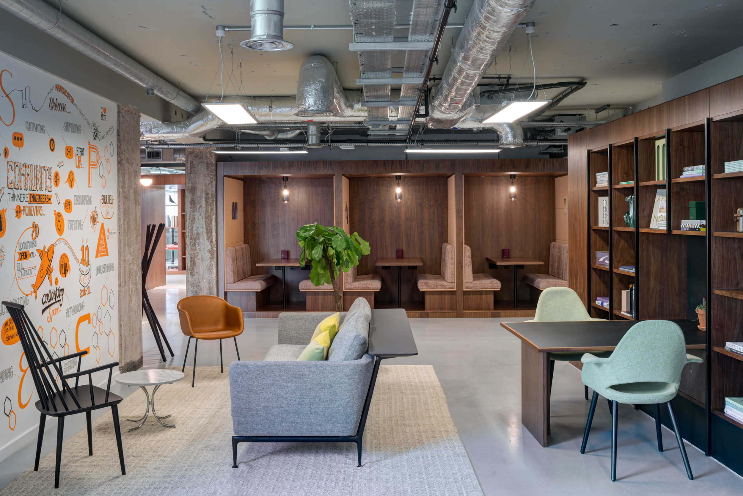 Breakout space at Spaces Peter House featuring wall art, cosy booths, and a bookshelf-lined wall divider.