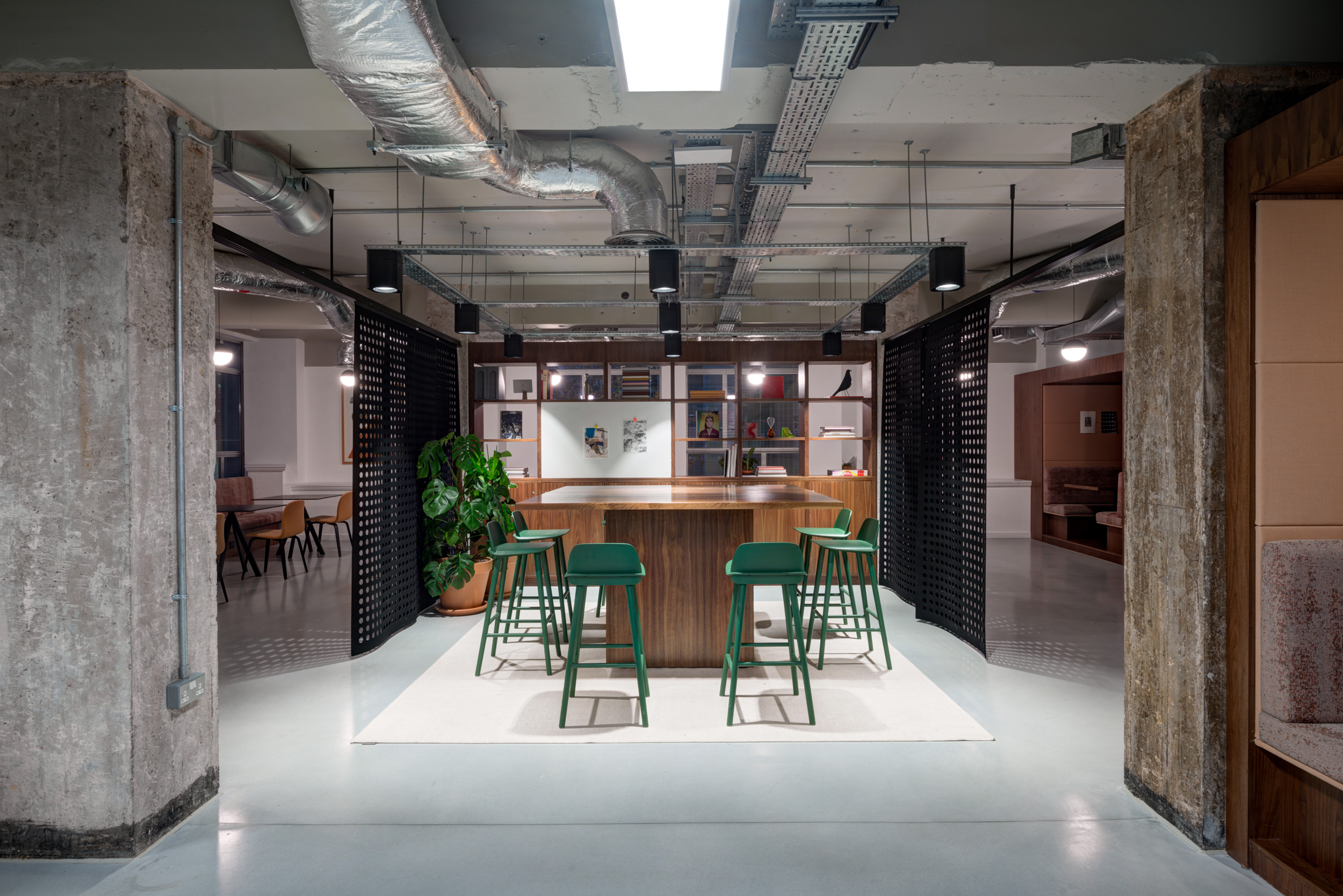 Communal high table with green barstools and exposed ductwork of Spaces Peter House.