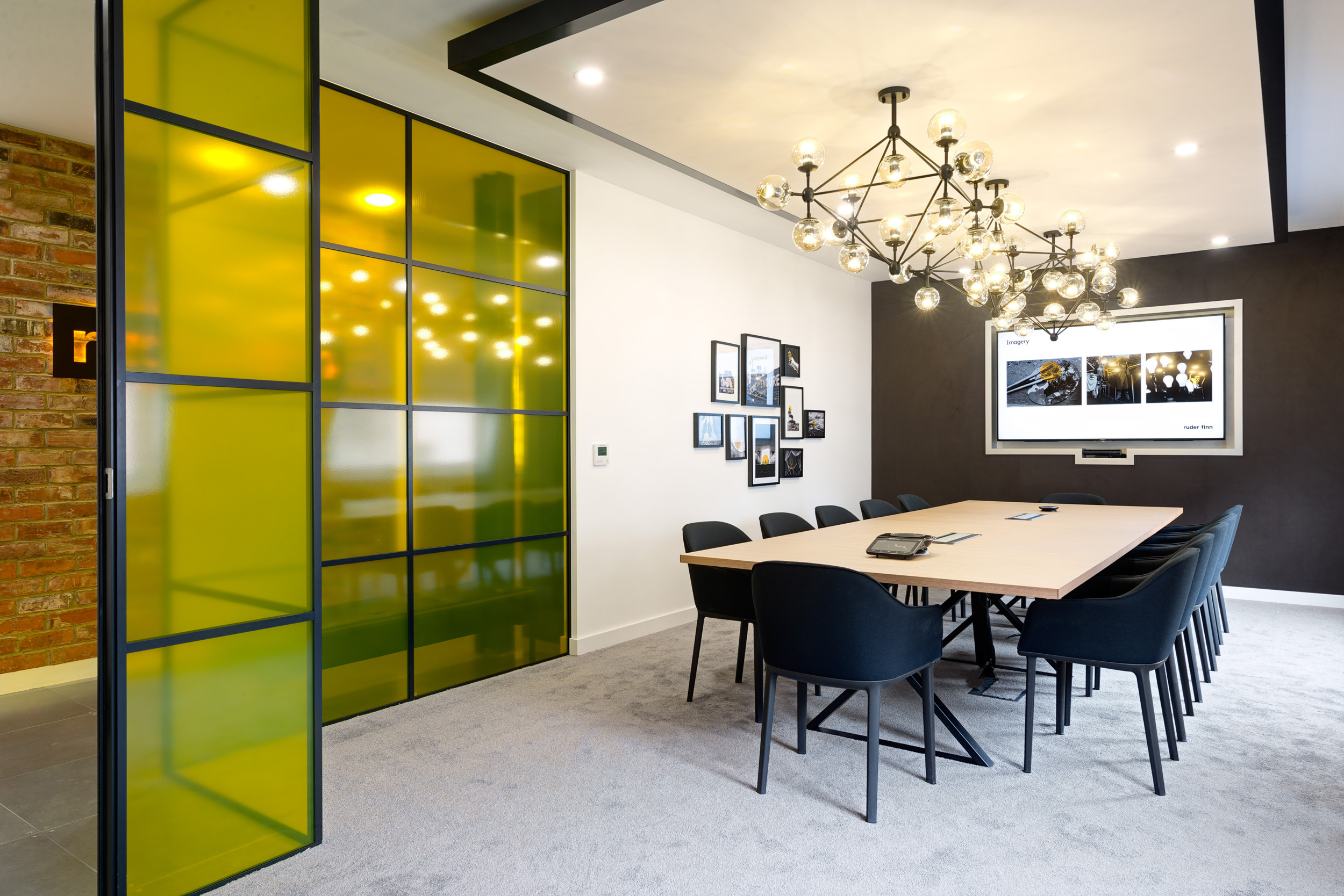Ruderfinn’s spacious conference room, designed by Modus Workspace, with vibrant yellow glass panels, sleek modern lighting, and a large meeting table.