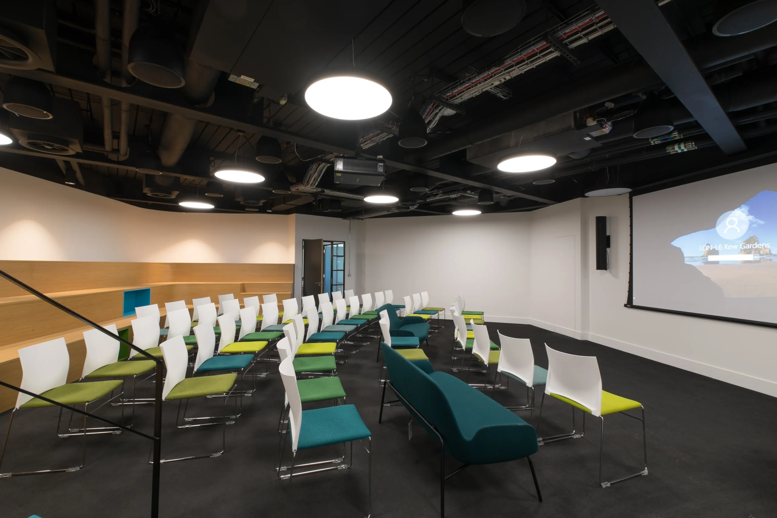 A flexible presentation space at Skyscanner’s office, arranged with colourful chairs and a large screen.