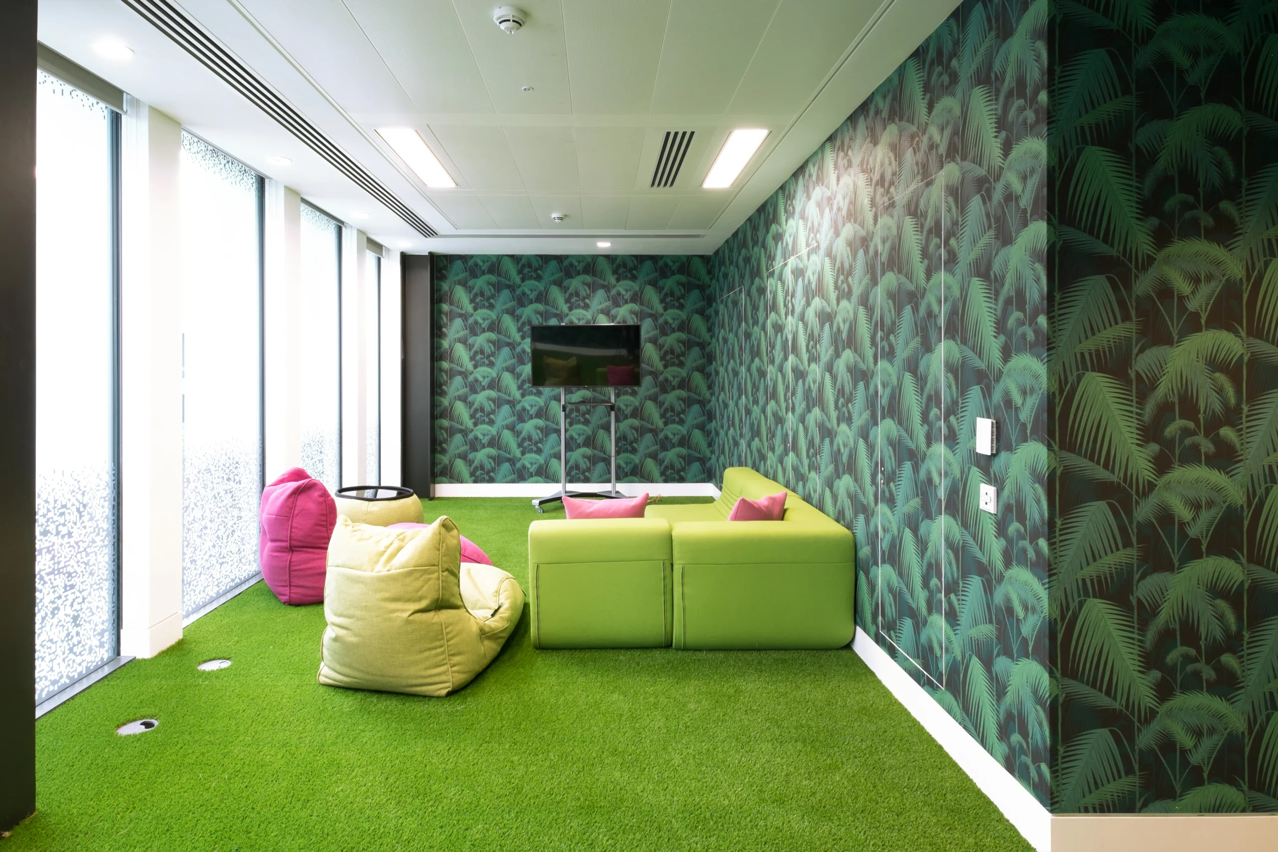 A breakout area at Skyscanner’s office with grass-style flooring, bean bags, and a green sofa.