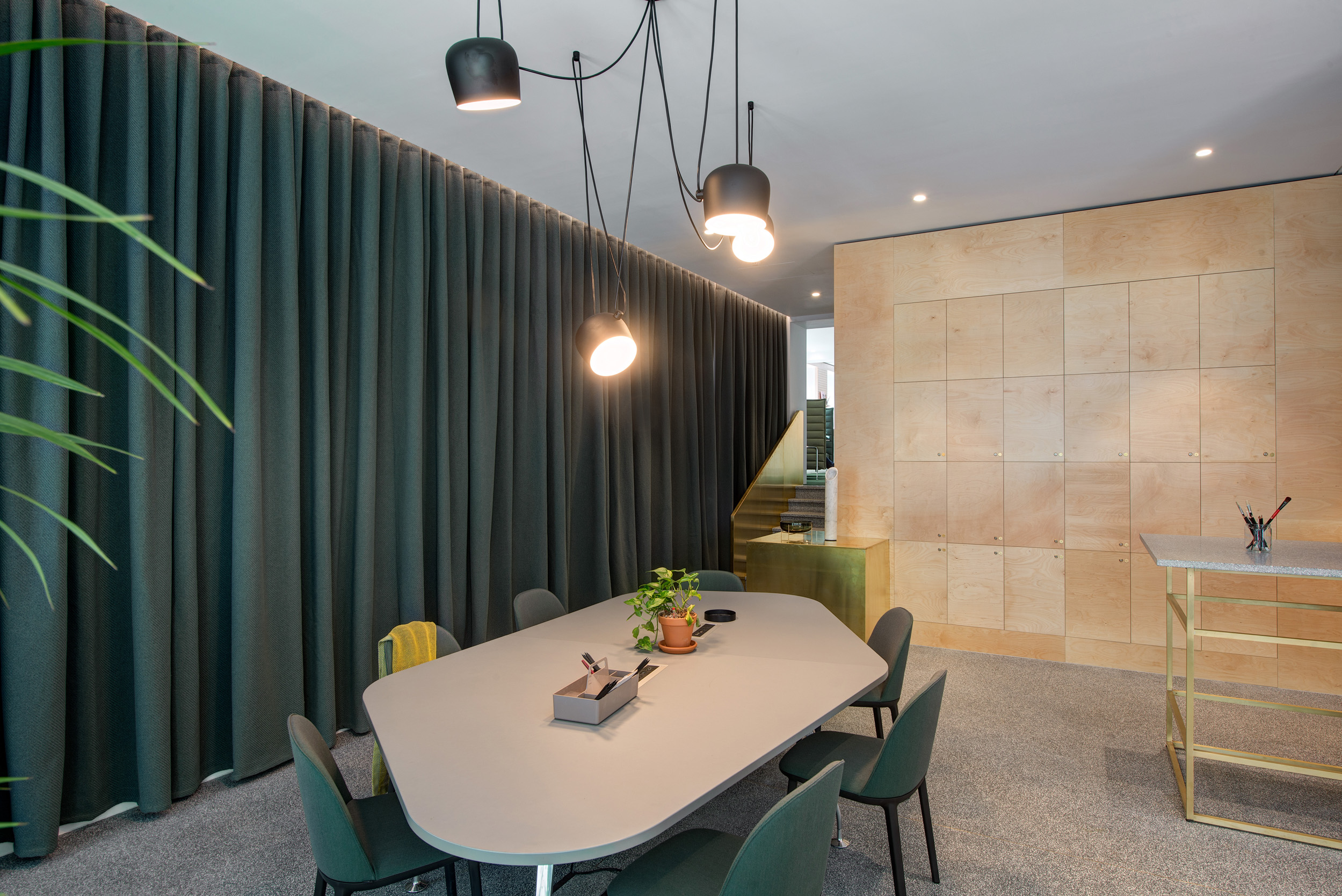A dark green curtain at Spaces Harley Building accented a meeting room with green chairs and pendant lighting.