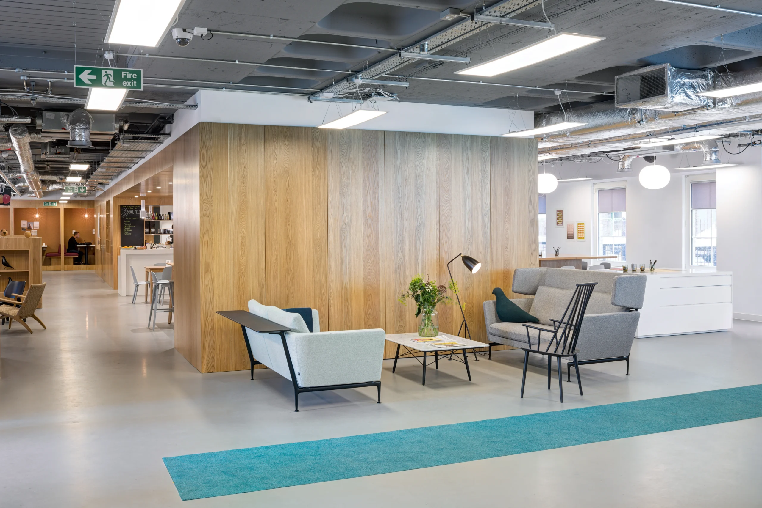 A breakout area in Spaces Mocatta House in Brighton showcases soft seating arrangements with the cafe in the background.