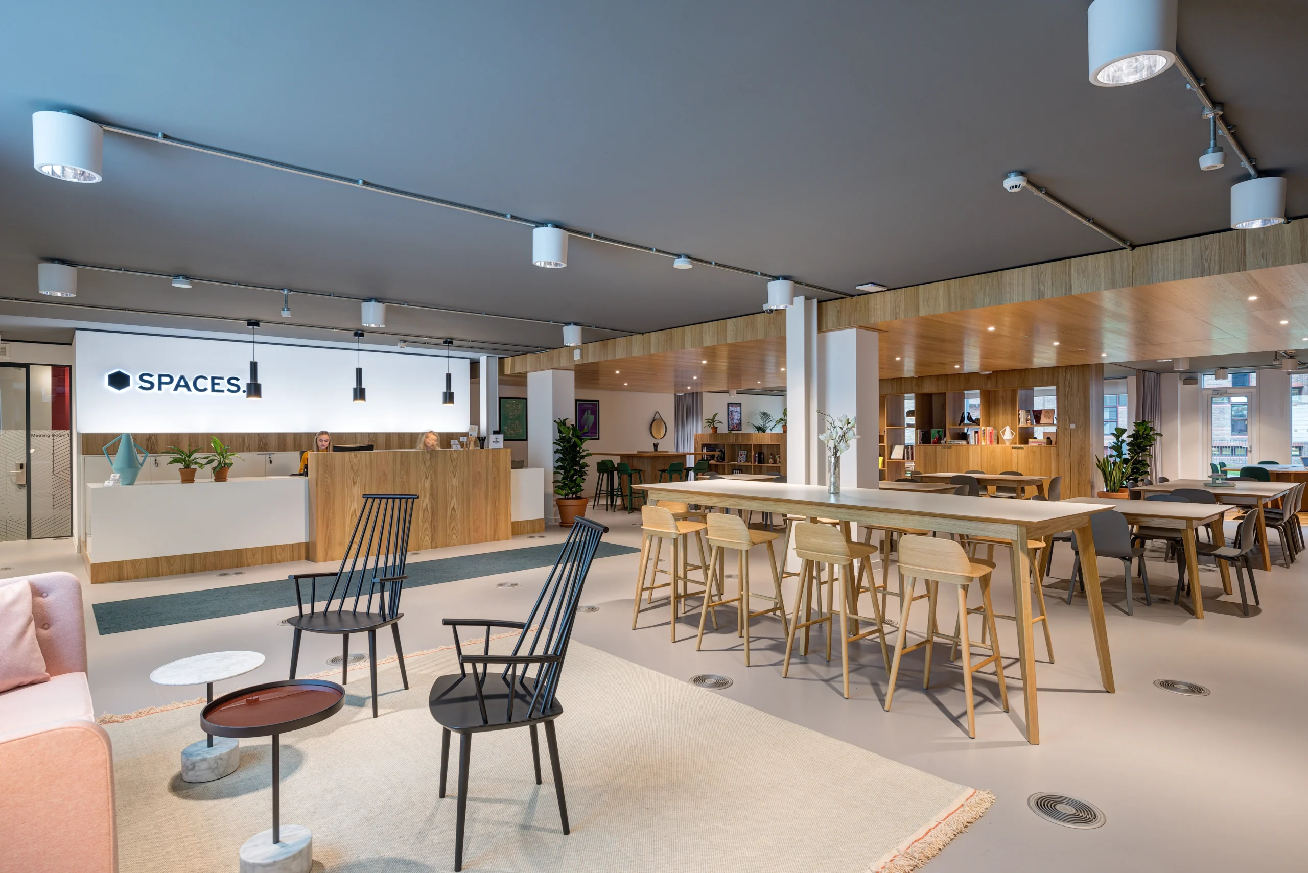 Reception area at Spaces Uxbridge with wooden decor, featuring a welcoming desk and open seating. The design highlights neutral tones and minimalistic furniture.