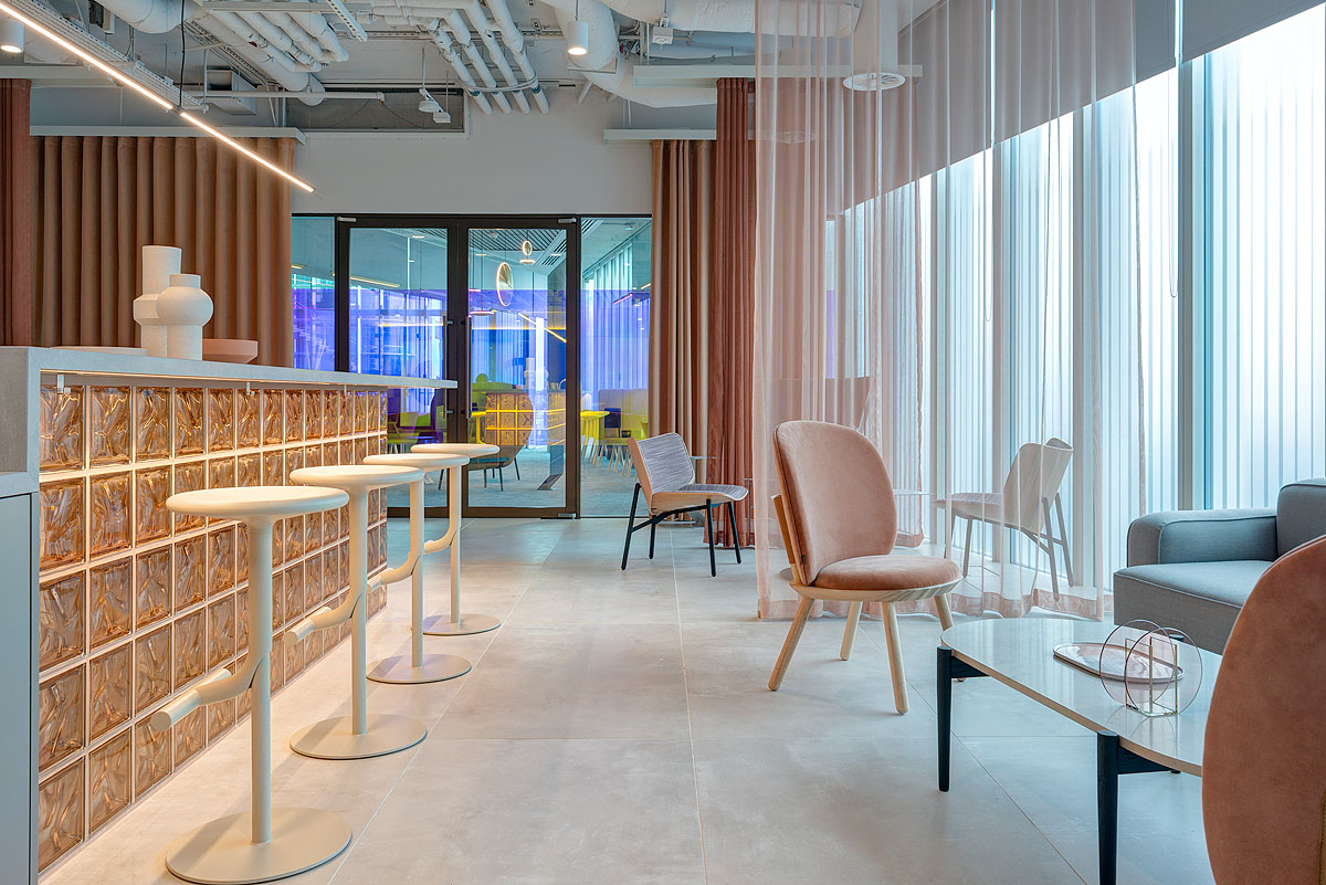 Versatile communal space at Storey - 2 Kingdom Street, designed by Modus Workspace. Open seating arrangements, mixed-use tables, and decorative elements like glass-tiled islands create a flexible area for informal meetings or relaxation.