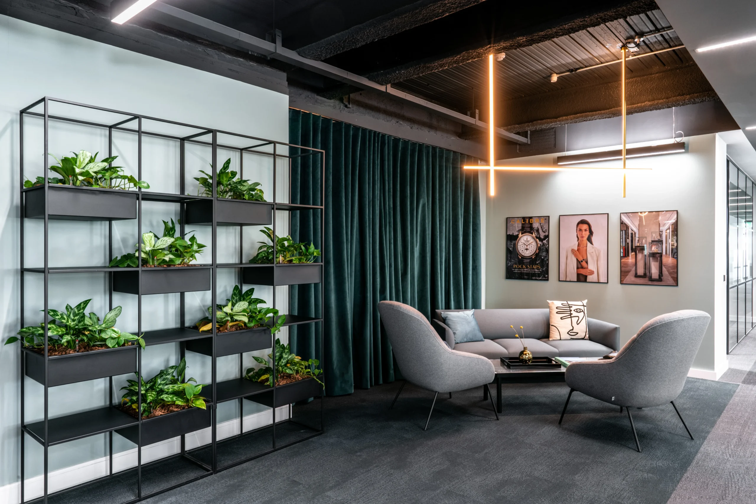 The Watches of Switzerland Group with biophilic plants, large pictured frames, and a grey sofa.