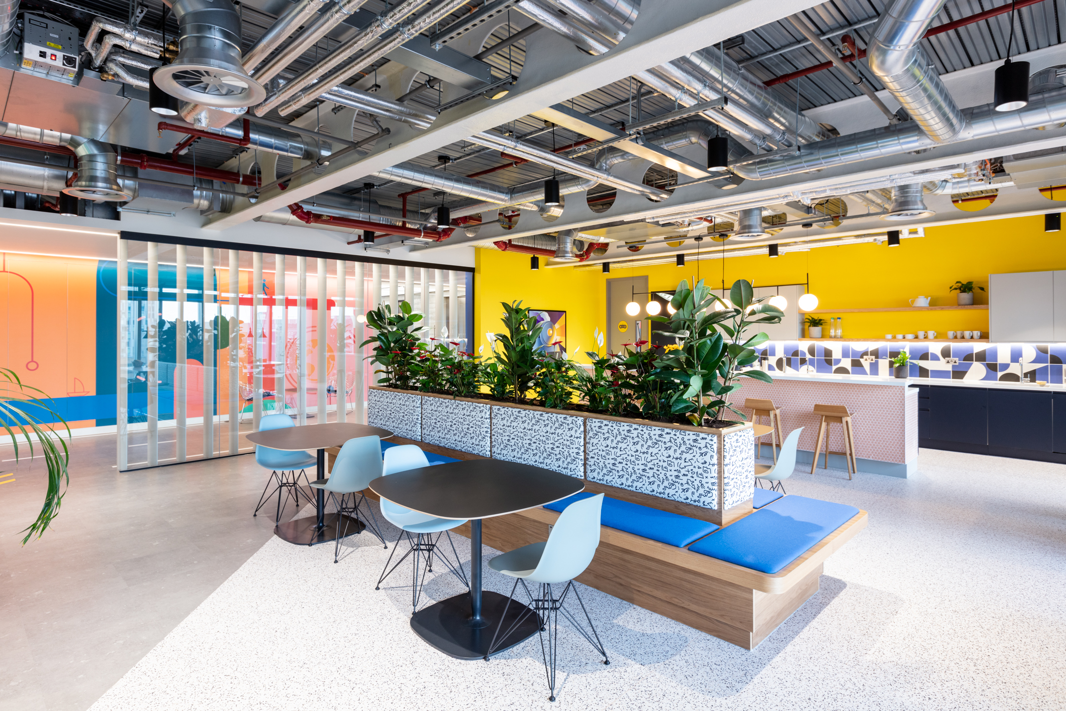 Travelfusion bepsoke teapoint, designed by Modus, featuring plotted plants, a large seating area and a vibrant yellow backwall.