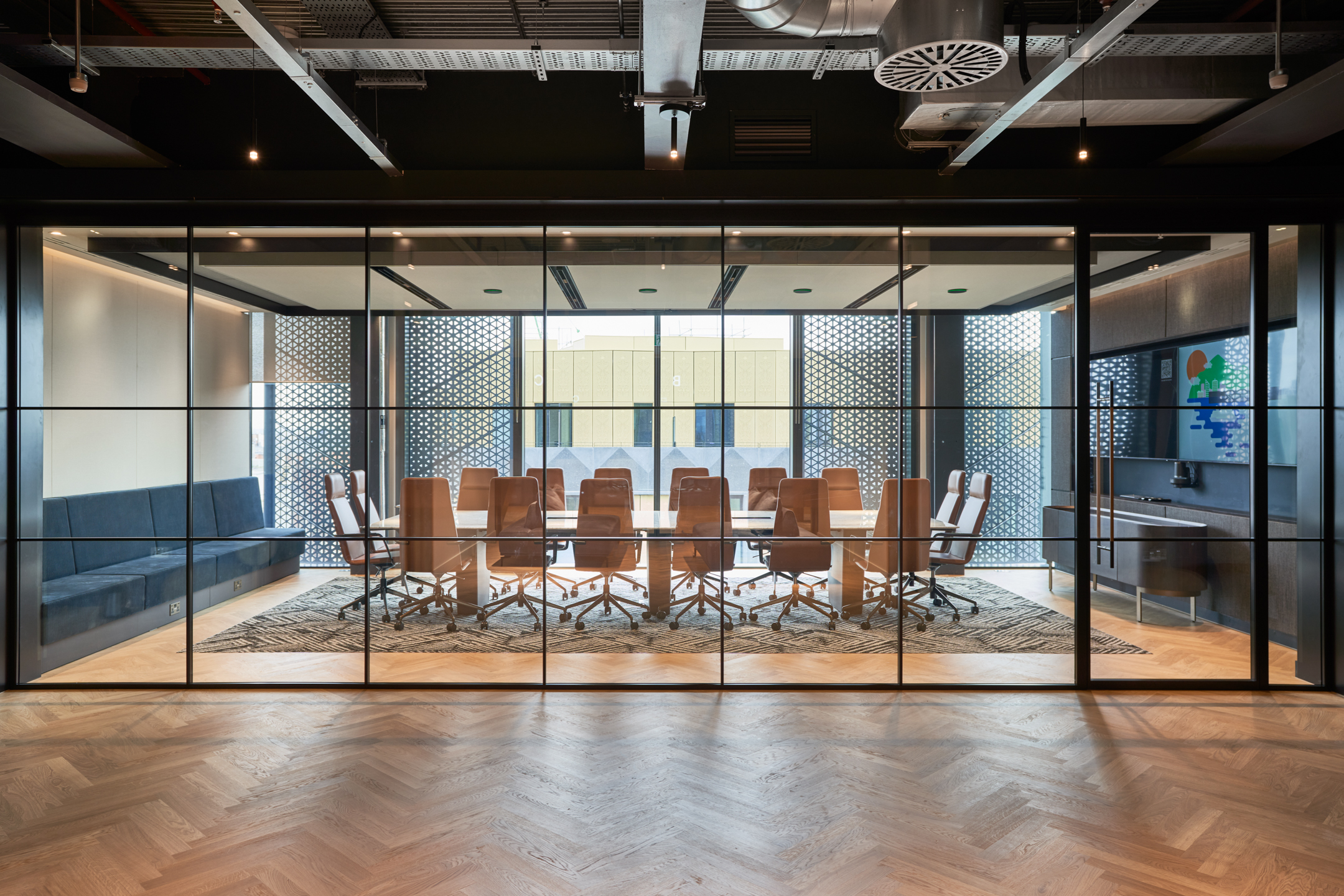 The conference room at United Talent Agency, designed by Modus, features a large wooden table surrounded by tan leather chairs, enclosed by glass partitions. This design maximises natural light and provides a modern, sophisticated setting for meetings and discussions.