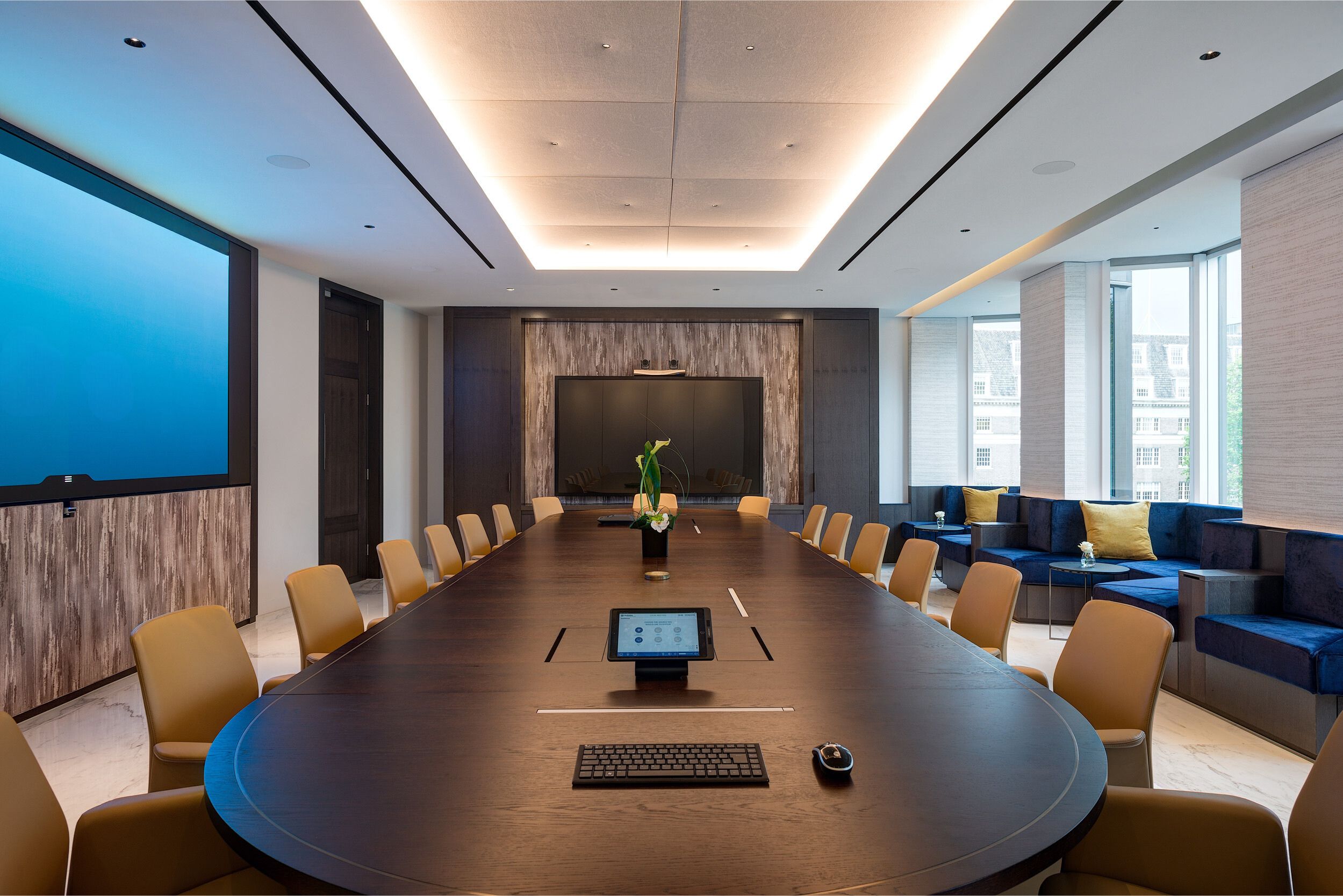 The boardroom at Vedanta, designed by Modus Workspace features a sleek dark wood table, tan leather chairs, and integrated technology for seamless meetings. The elegant lighting and minimalist decor create a professional yet inviting atmosphere.