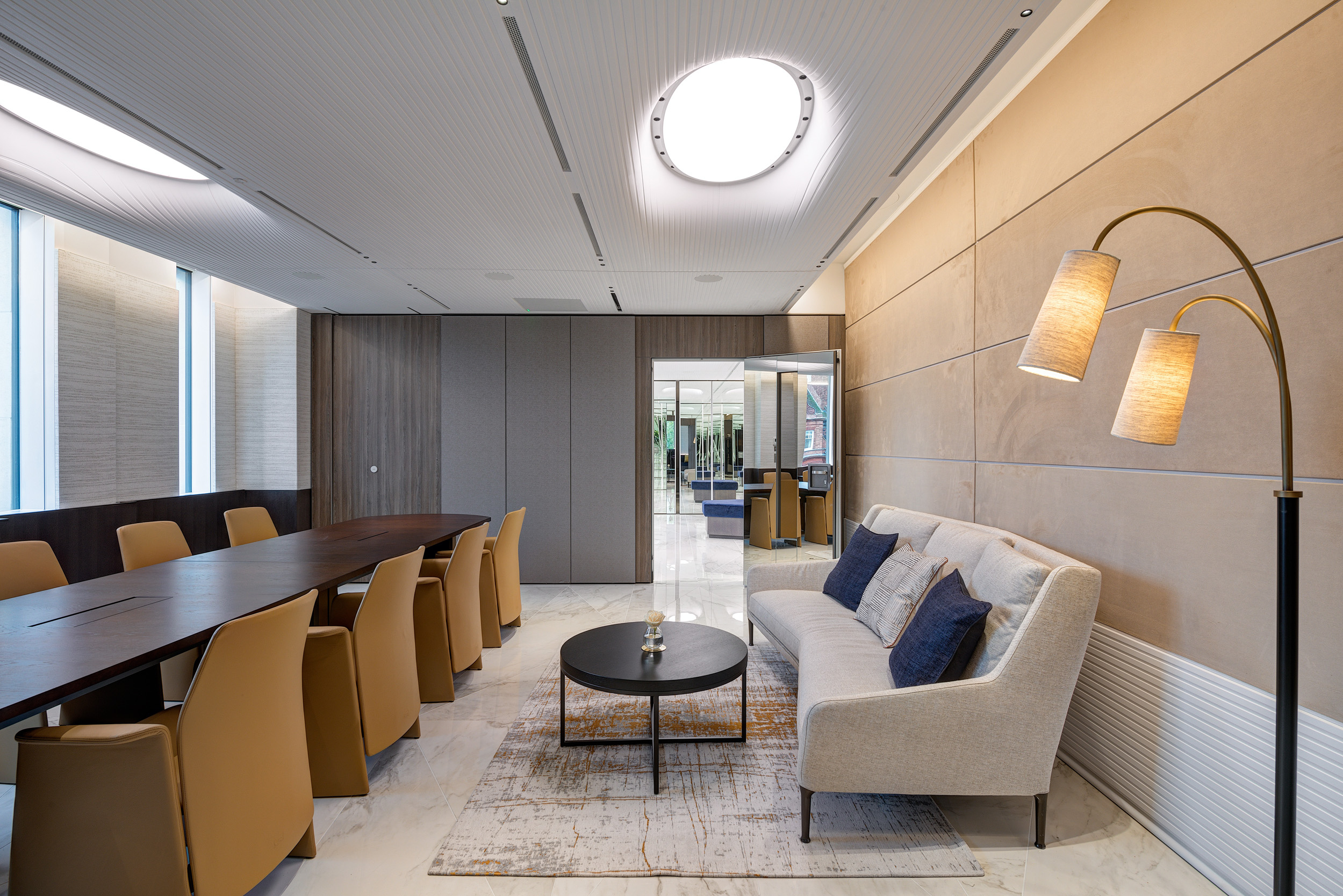 A meeting room at Vedanta, designed by Modus Workspace, features a dark wood conference table with plush seating and integrated technology. The modern lighting and lounge space ensure productive discussions in a refined setting.
