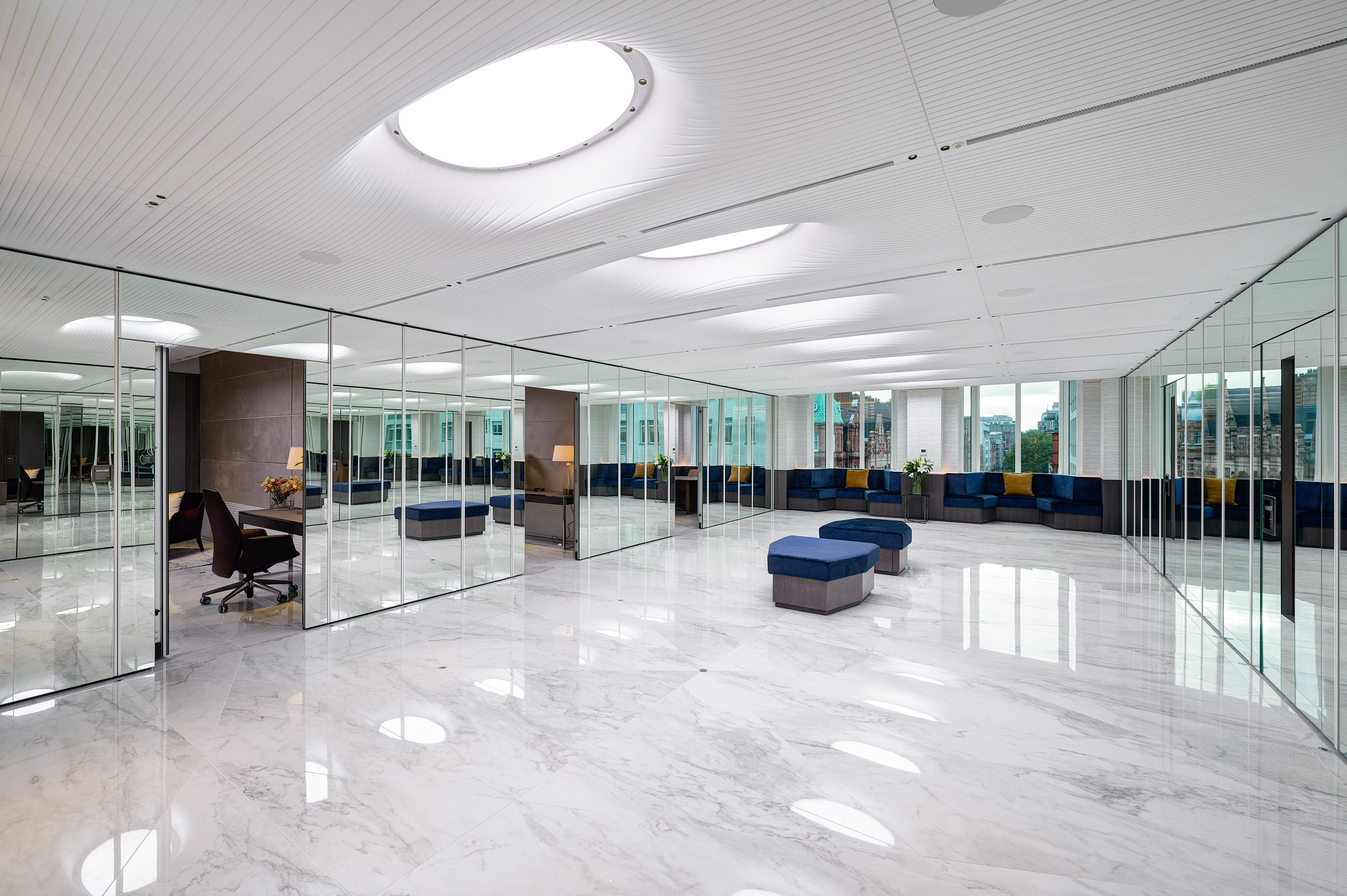 Private Meeting Room at Vedanta, Designed by Modus Workspace. This meeting space blends modernity and comfort with a round table, tan leather chairs, and a skylight. A cozy sofa adds versatility to the room, making it perfect for confidential meetings.