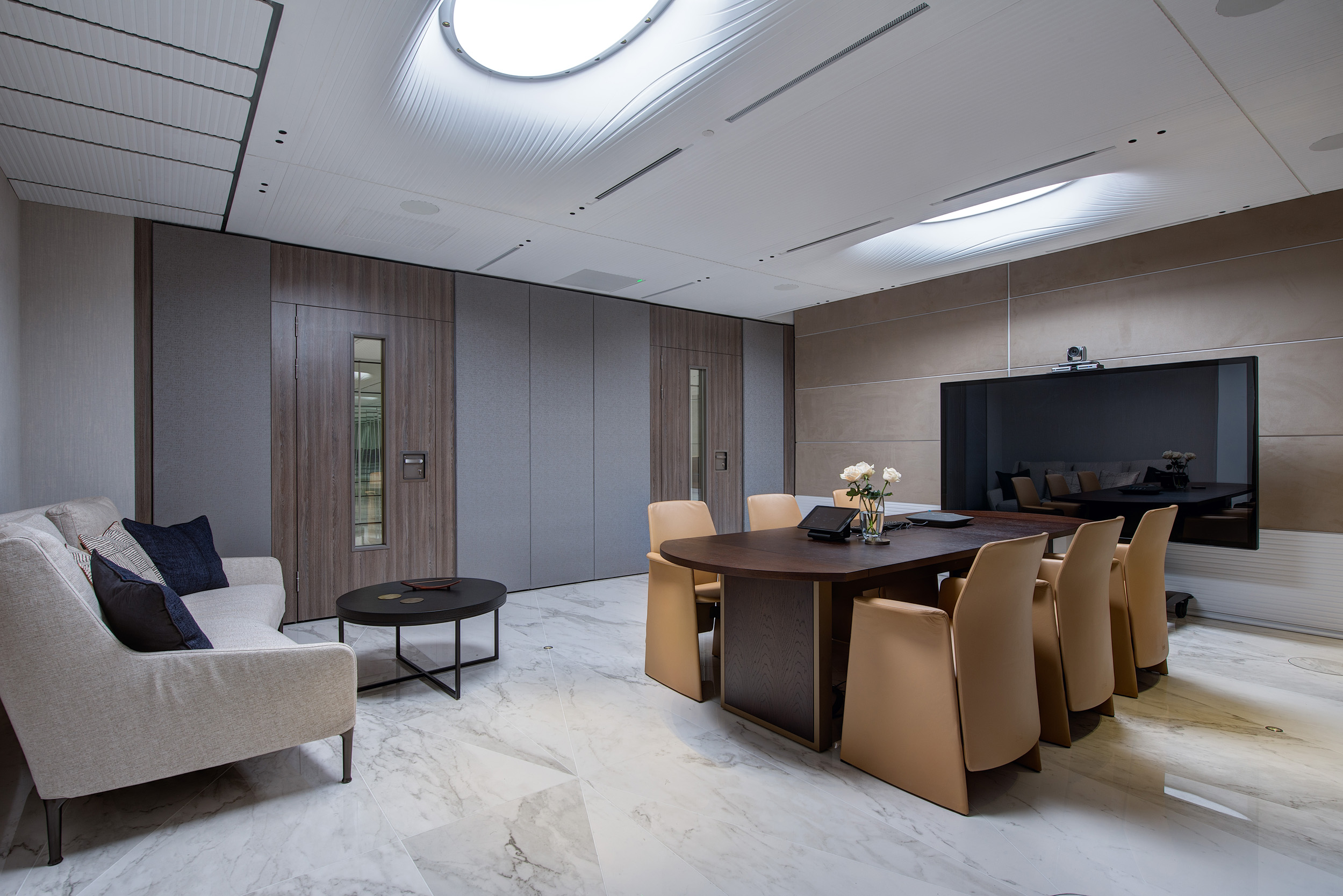 Reception at Vedanta, Designed by Modus Workspace featuring marble floors and sleek wood panelling, creating a welcoming space. The lighting enhances the polished finishes, setting a luxurious tone for visitors.